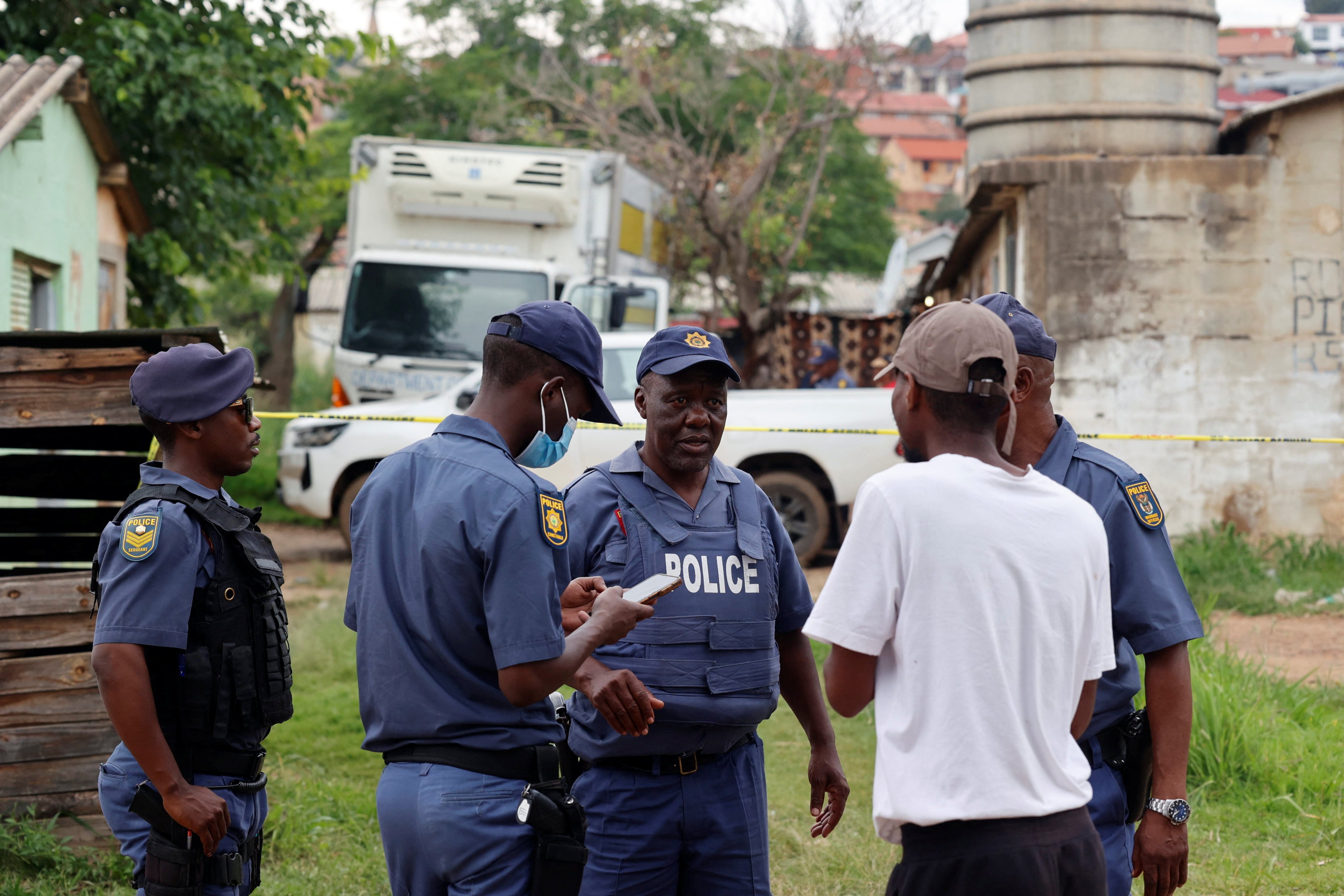 Police speak to a resident at Saulsville Hostel in Atteridgeville on Saturday. Photo: Reuters