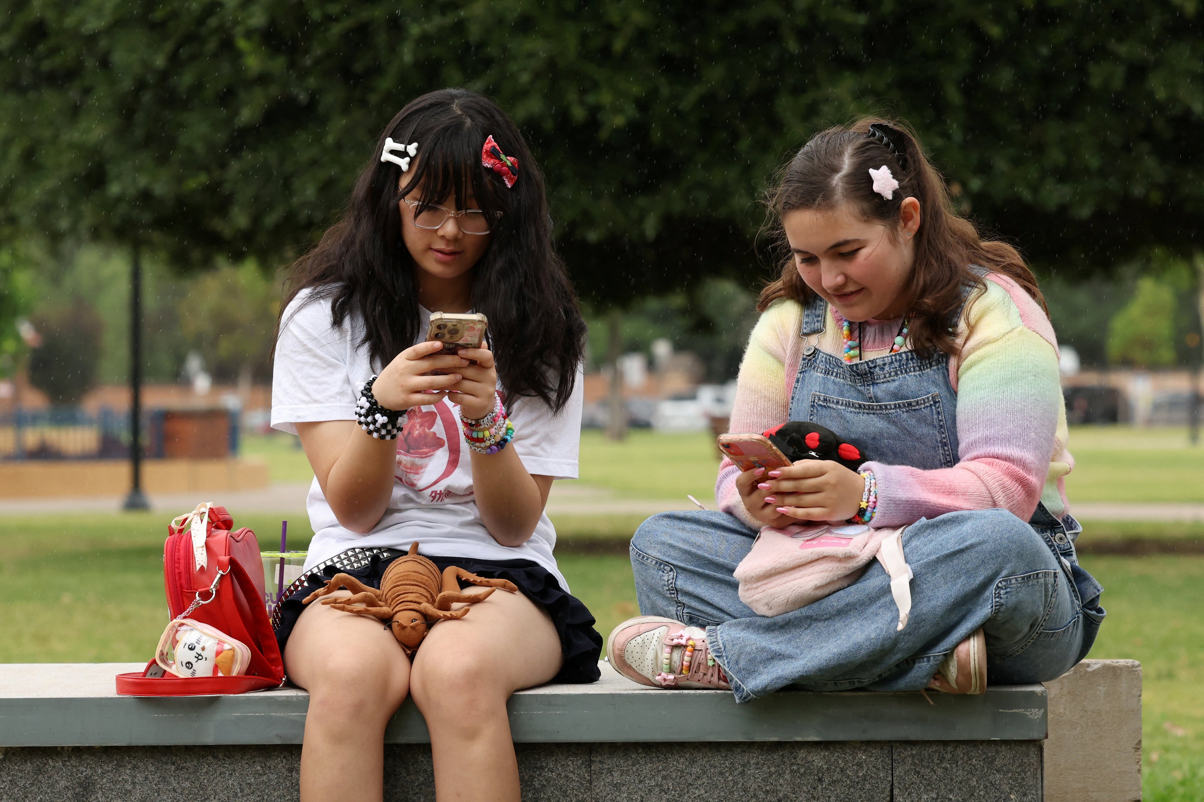 Australian teens Annie Wang (left), 14, and Ayris Tolson, 15, check their phones a few days before Australia’s social media ban for users under 16 is scheduled to take effect on December 10. Photo: Reuters