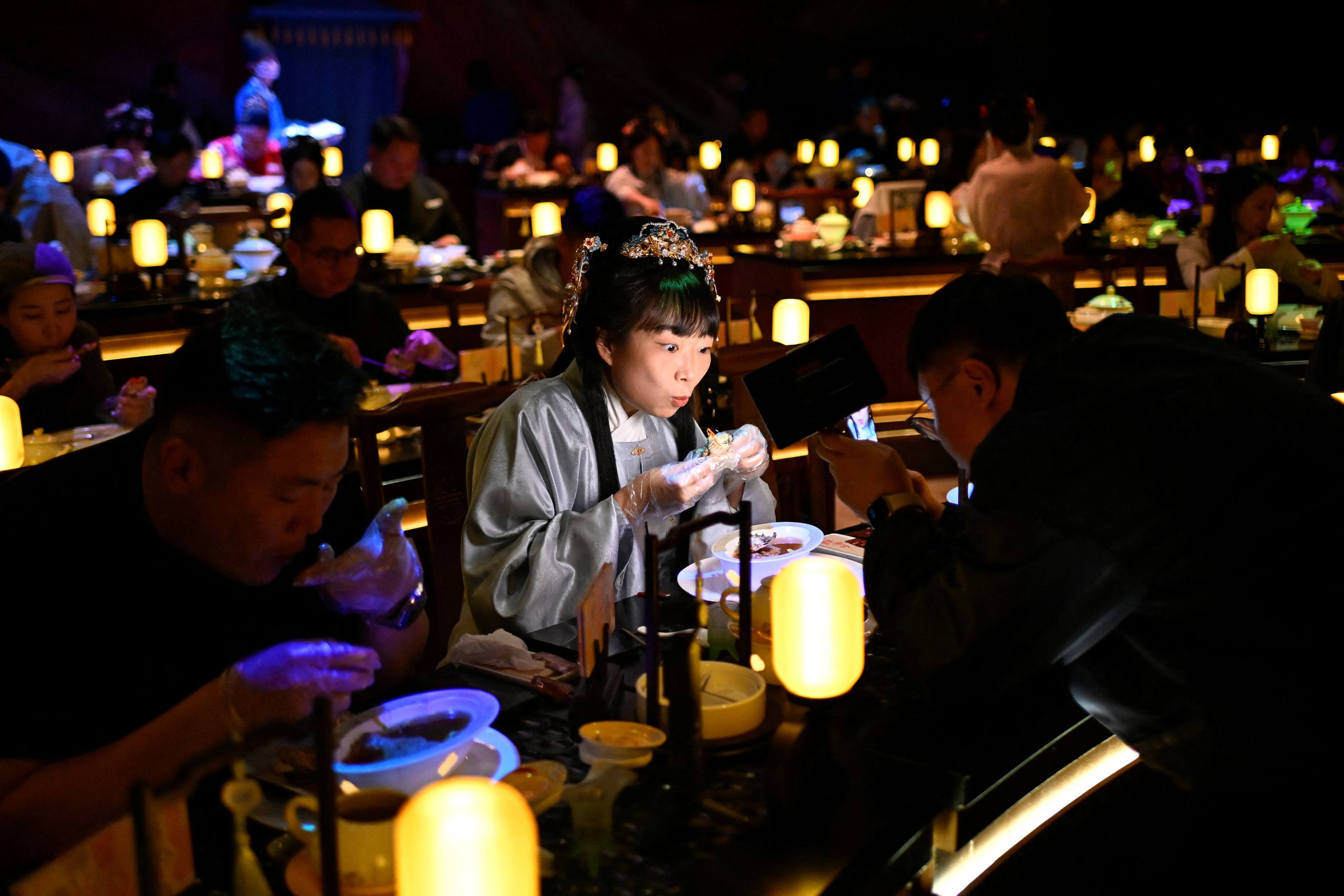 A woman in traditional Chinese clothes and accessories dines at a theatrical restaurant in Beijing. Photo: AFP