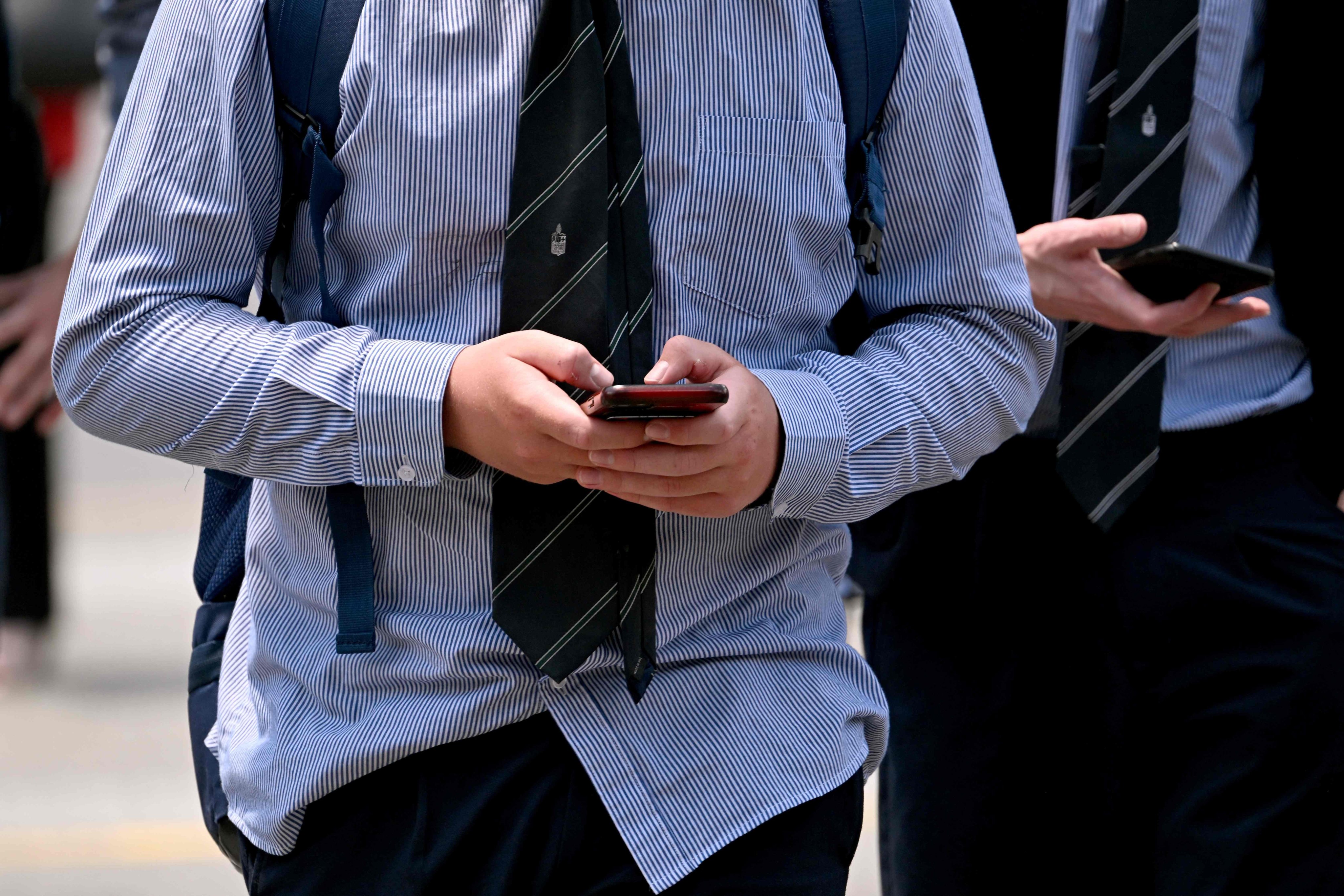A schoolboy looks at his phone in Melbourne on November 27, 2024. Australia will ban young teenagers from social media on December 10, launching a world-first crackdown designed to unglue children from addictive scrolling on the likes of Facebook, Instagram and TikTok. Photo: AFP