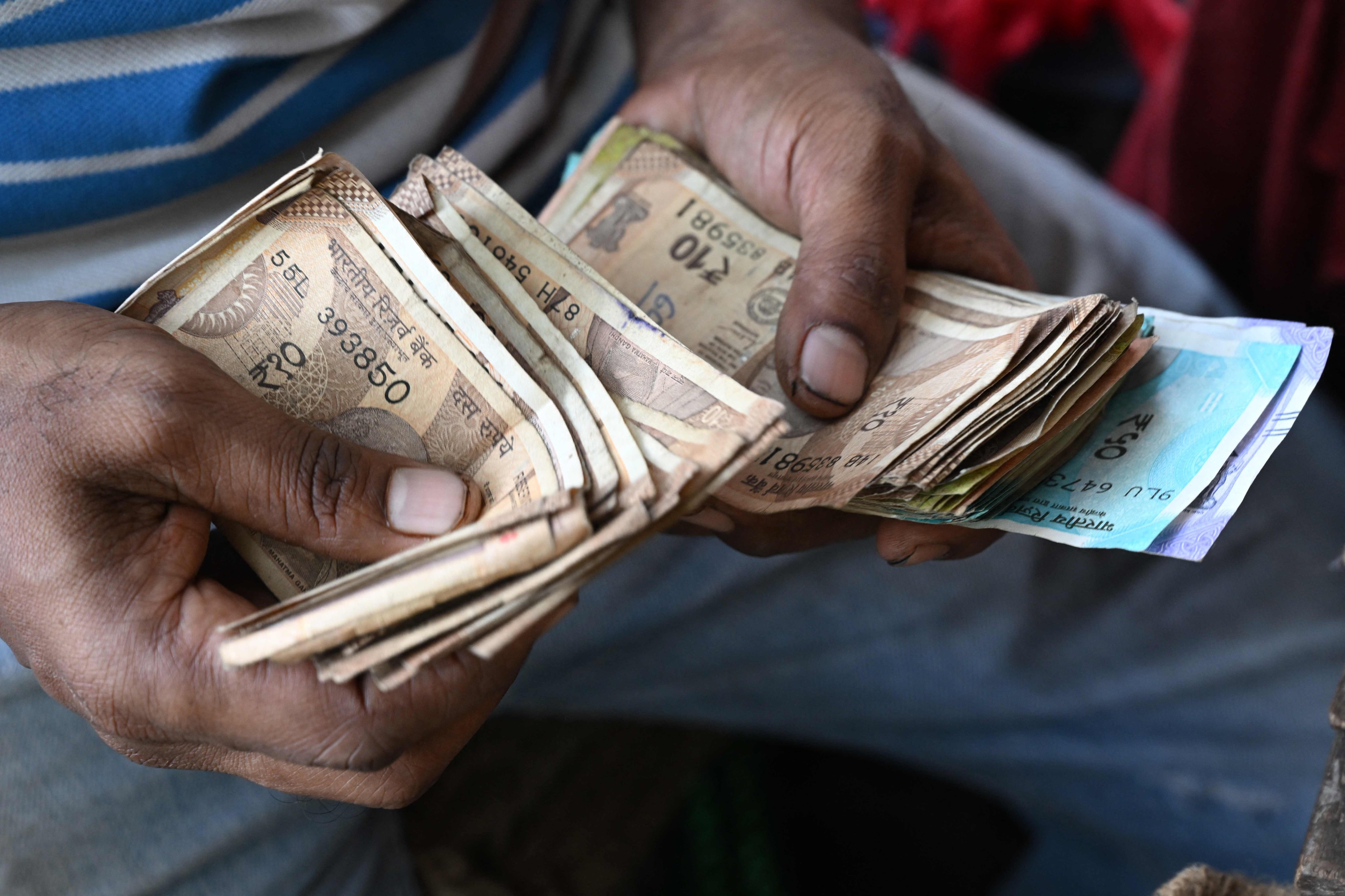 A roadside vendor counts Indian rupee notes in Mumbai on November 28. Photo: AFP