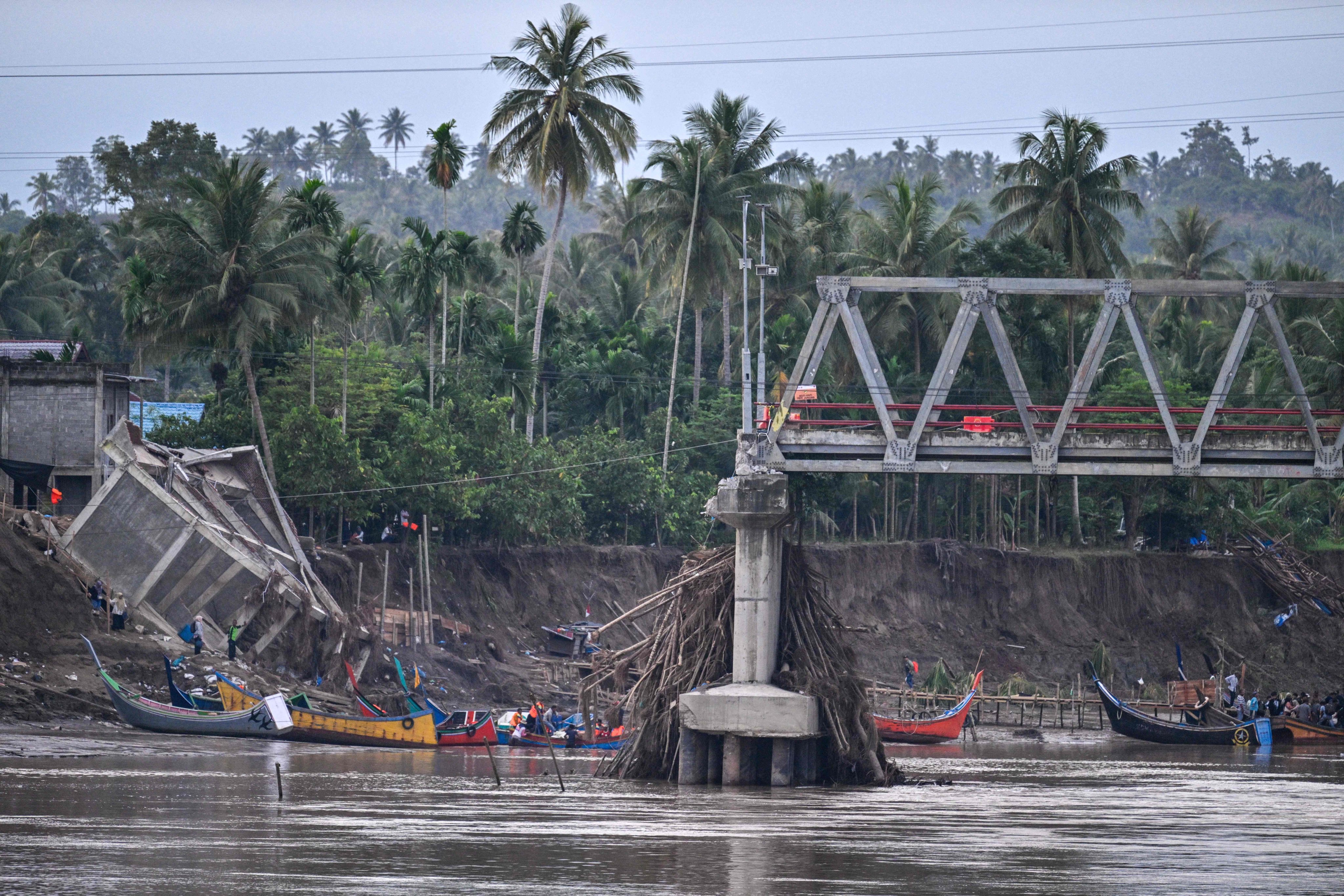 Boats used to ferry passengers across a river are seen near a collapsed bridge in Indonesia’s Aceh province in the aftermath of deadly flash floods this month. Photo: AFP