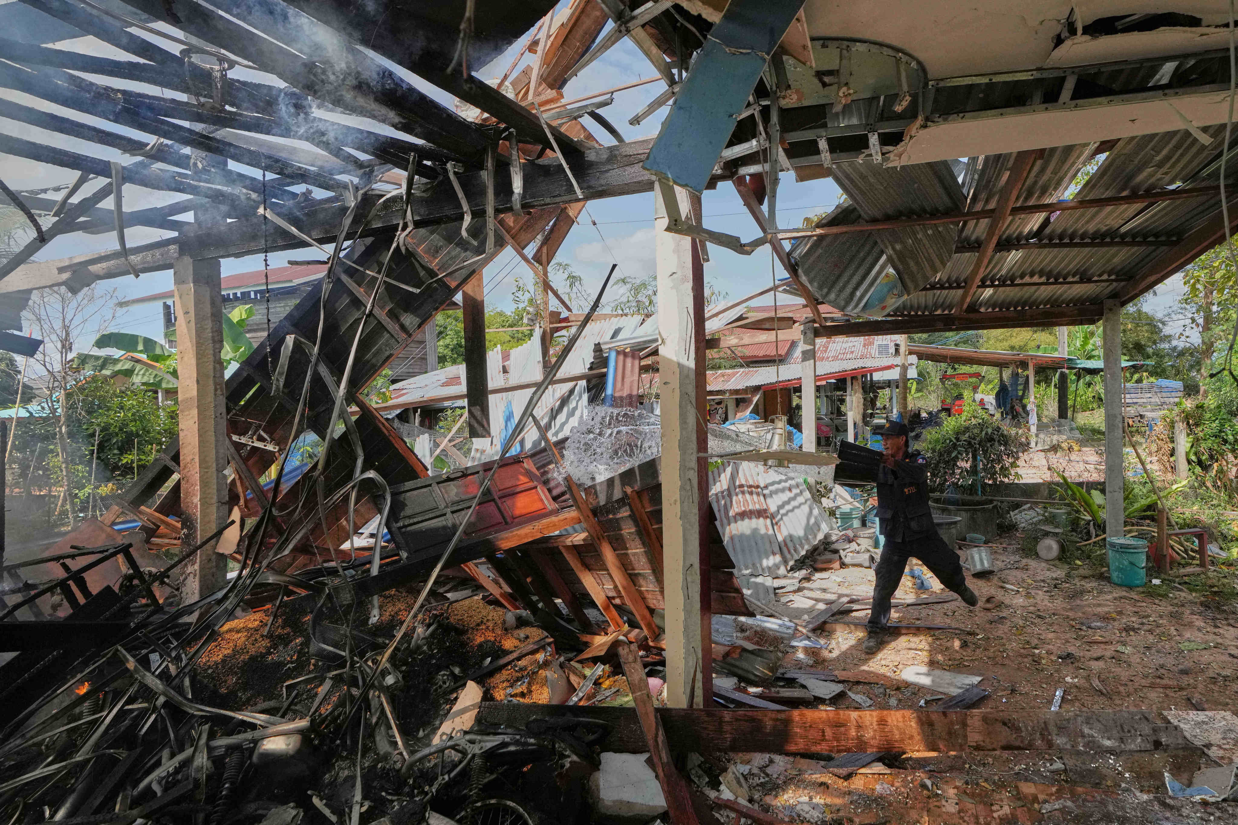 A village security volunteer splashes water to control a fire at a house after what a Thai soldier said was a Cambodian artillery strike in the area in Sisaket province, Thailand on Sunday. Photo: AP