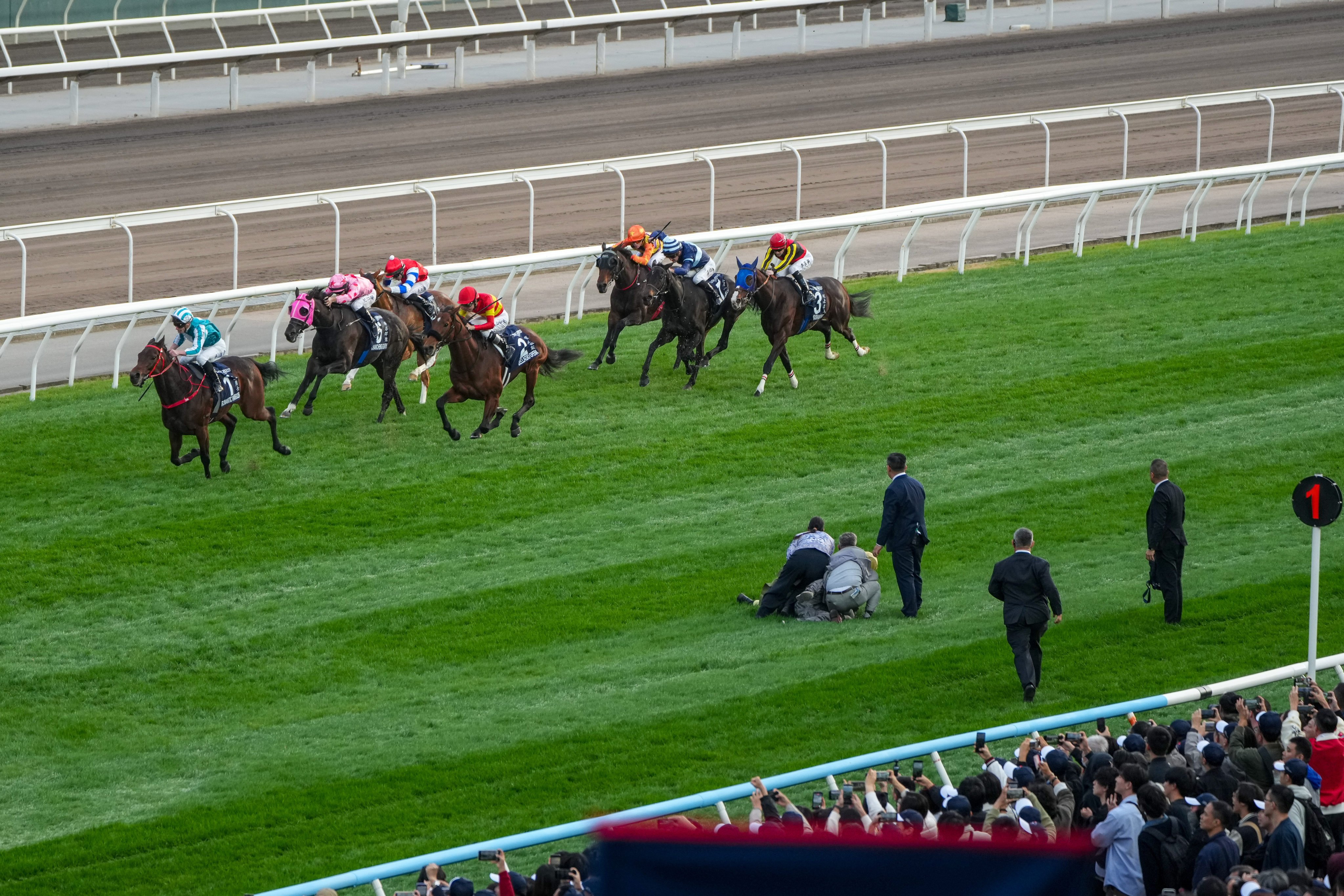 Jockey Club officials hold a man who ran onto the track down during Sunday’s Hong Kong Cup at Sha Tin. Photos: Kenneth Chan
