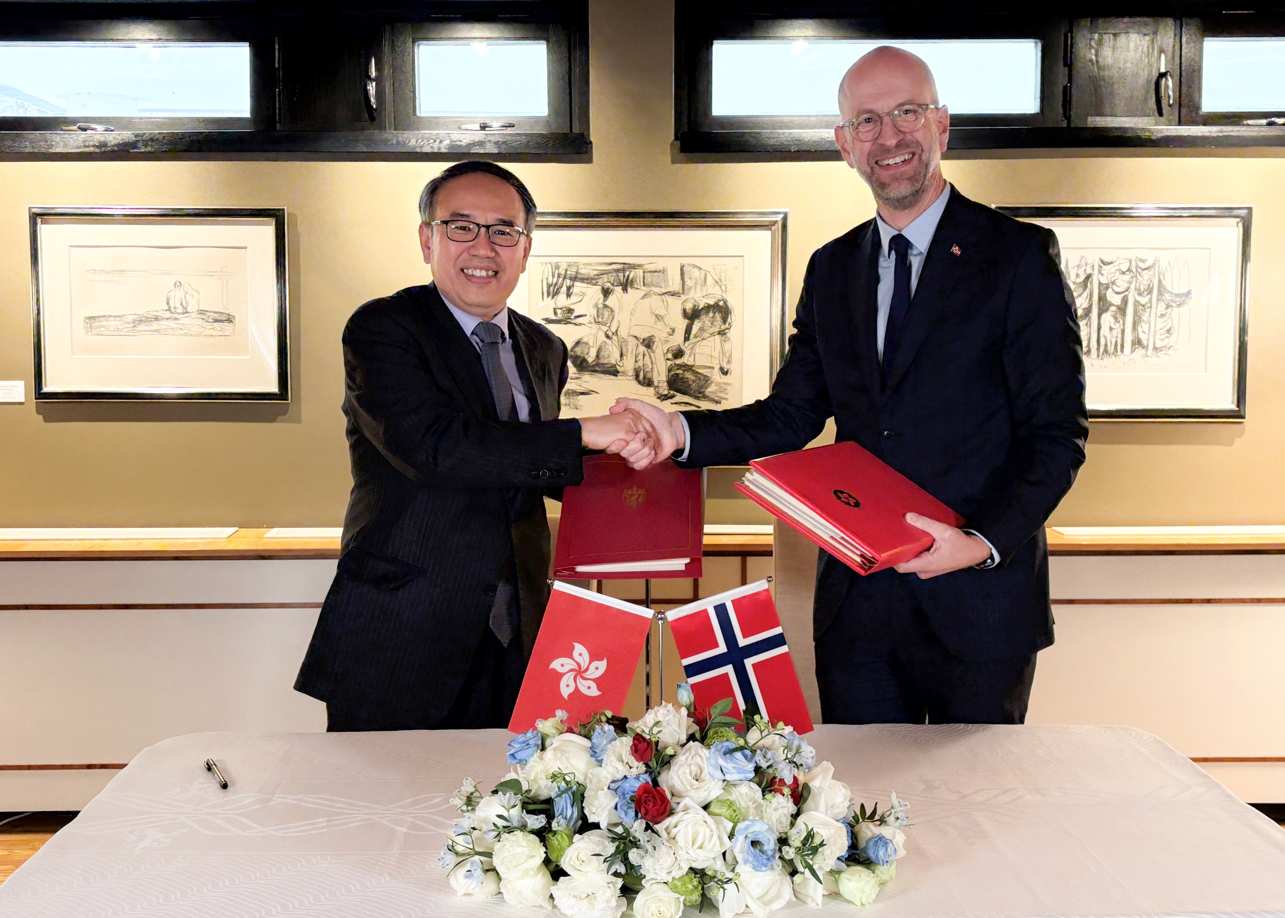 Hong Kong Secretary for Financial Services and the Treasury Christopher Hui (left), exchanges documents with Norway’s Ambassador to China, Vebjørn Dysvik, in Beijing on Tuesday. Photo: Handout