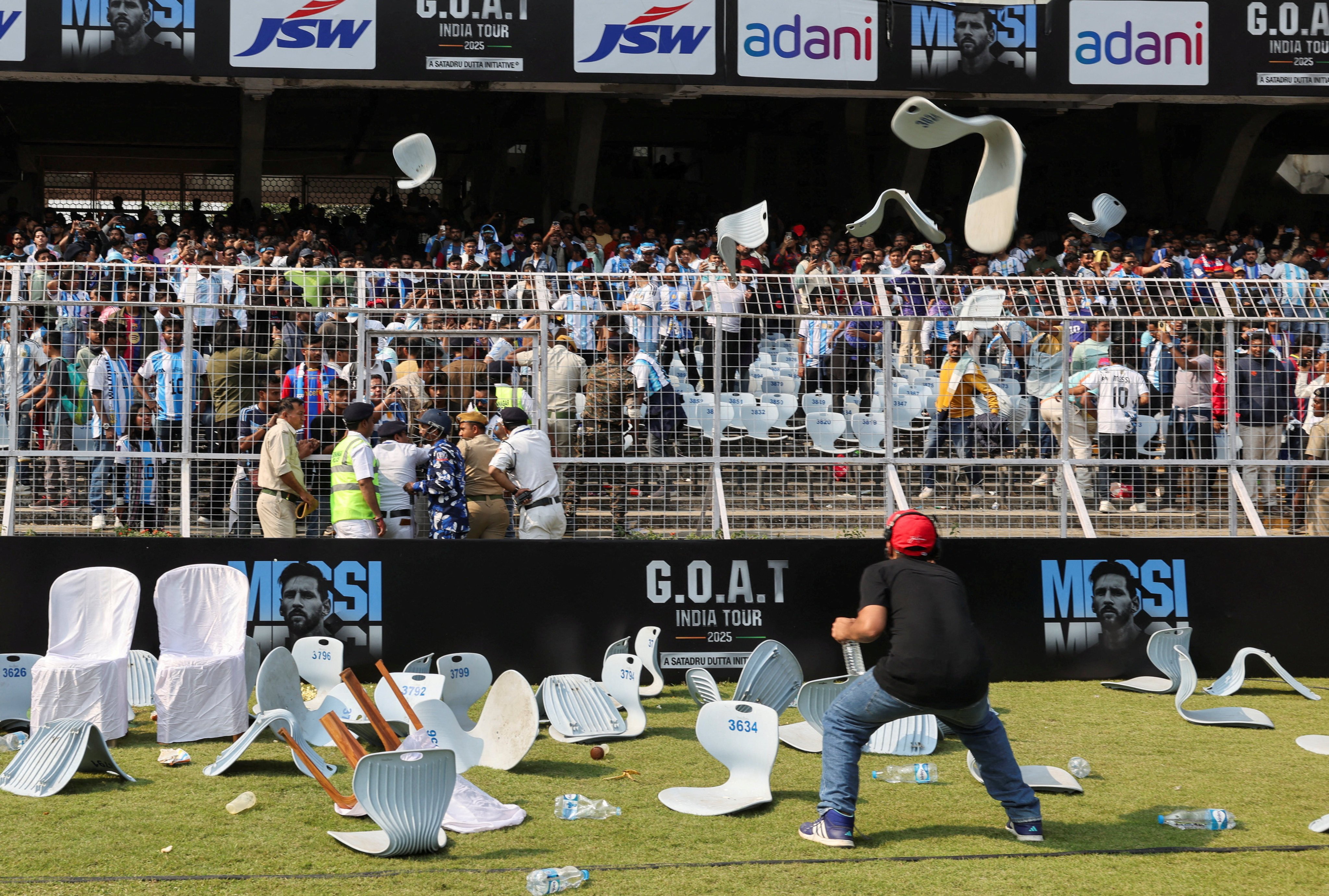 A man ducks to avoid chairs being thrown by fans after Argentine football star Lionel Messi leaves the Salt Lake Stadium during his tour in Kolkata on Saturday. Photo: Reuters