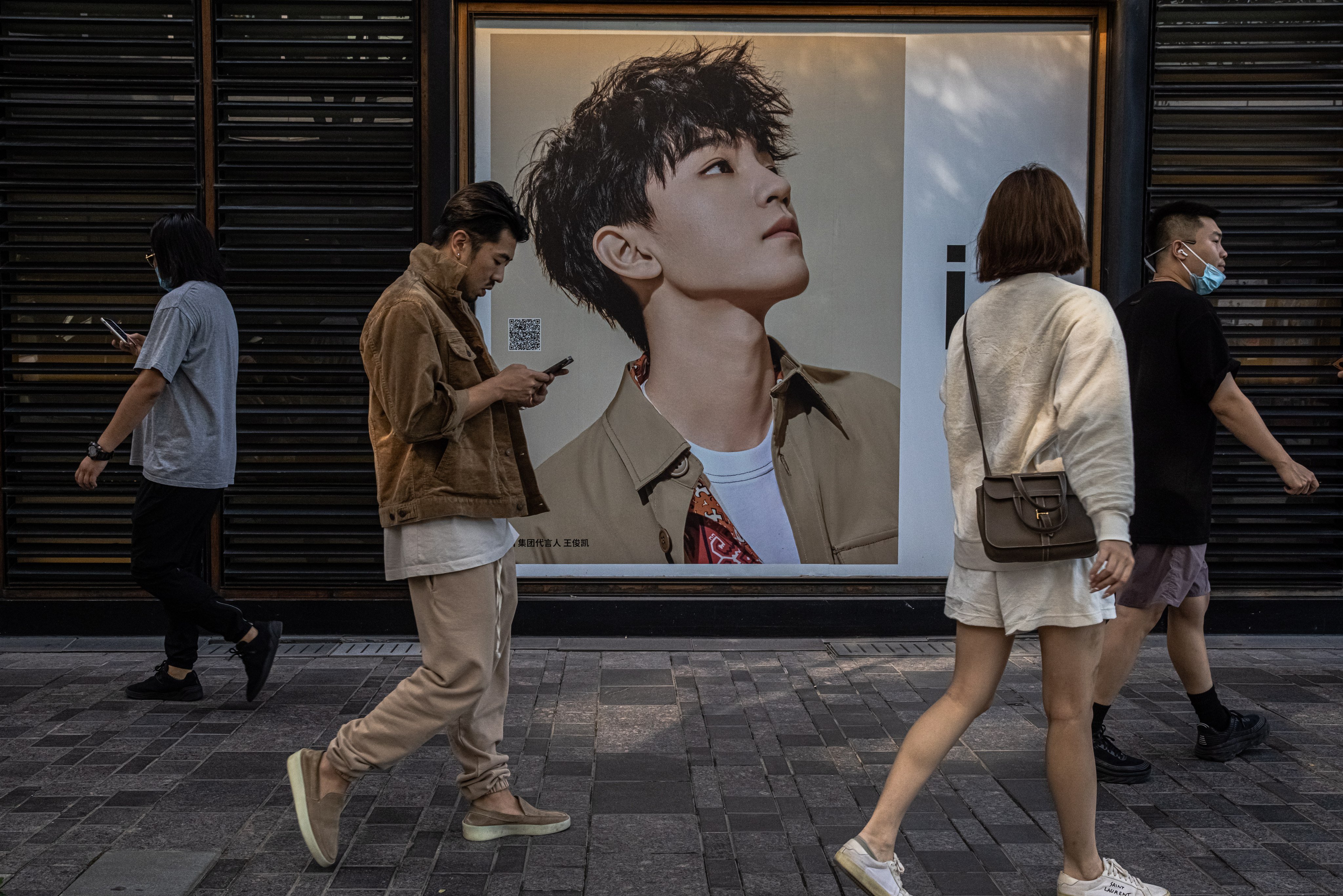 People walk past an advertisement in the shopping area of Sanlitun in Beijing. Photo: EPA-EFE