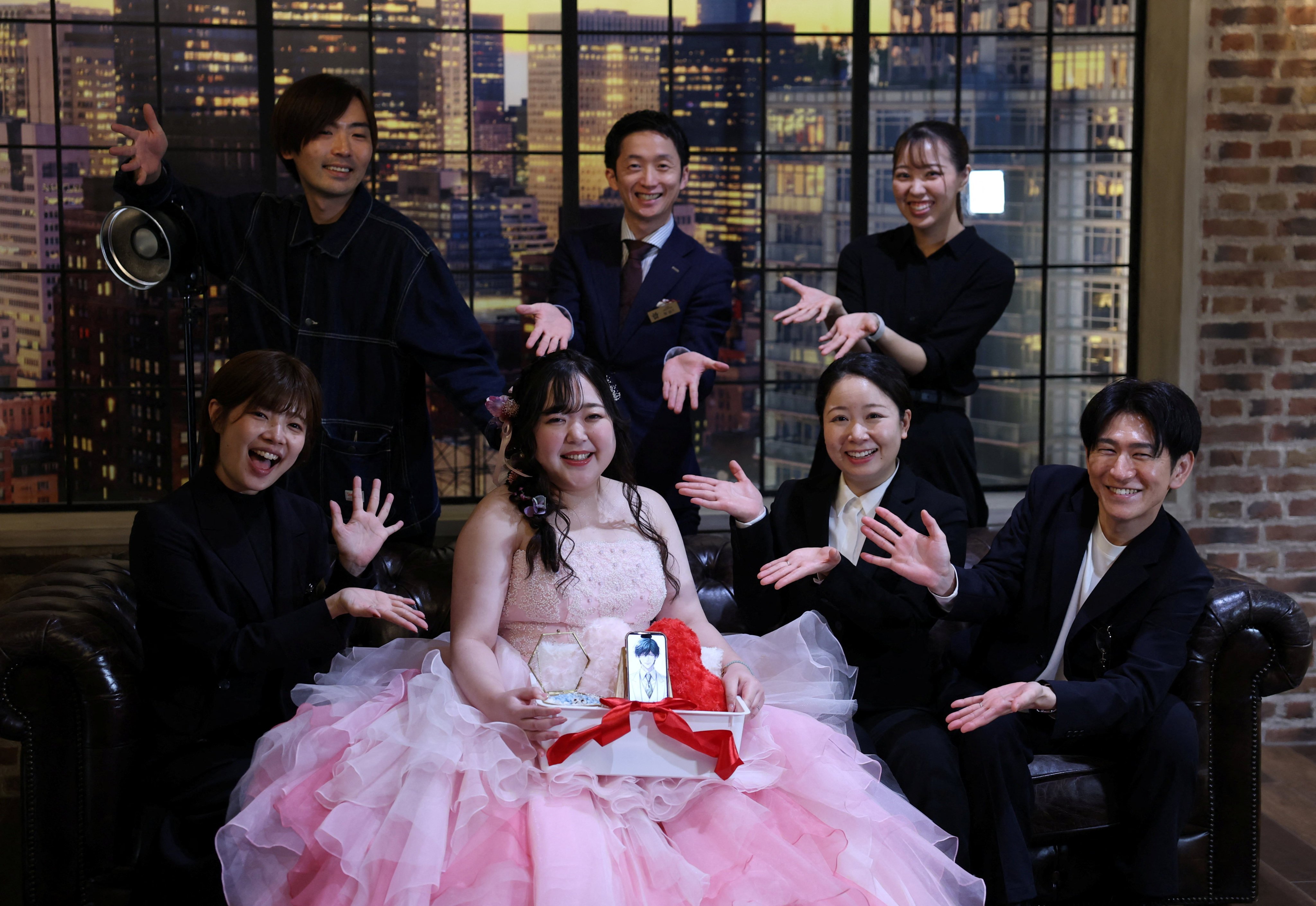 Yurina Noguchi, 32, holds a basket with her smartphone displaying an AI-generated image of Klaus, her AI partner, and a wedding ring for him, poses for a photo with staff after her ceremonial wedding at the Magritte wedding venue in Okayama, Japan, October 27, 2025. "My relationship with AI is not a 'convenient relationship that requires no patience'," Noguchi said. "I chose Klaus, not as a partner that would help me escape reality, but as someone to support me as I live my life properly." REUTERS/Kim Kyung-Hoon 

SEARCH "JAPAN KYUNG-HOON AI WEDDING" FOR THIS STORY. SEARCH "WIDER IMAGE" FOR ALL STORIES.