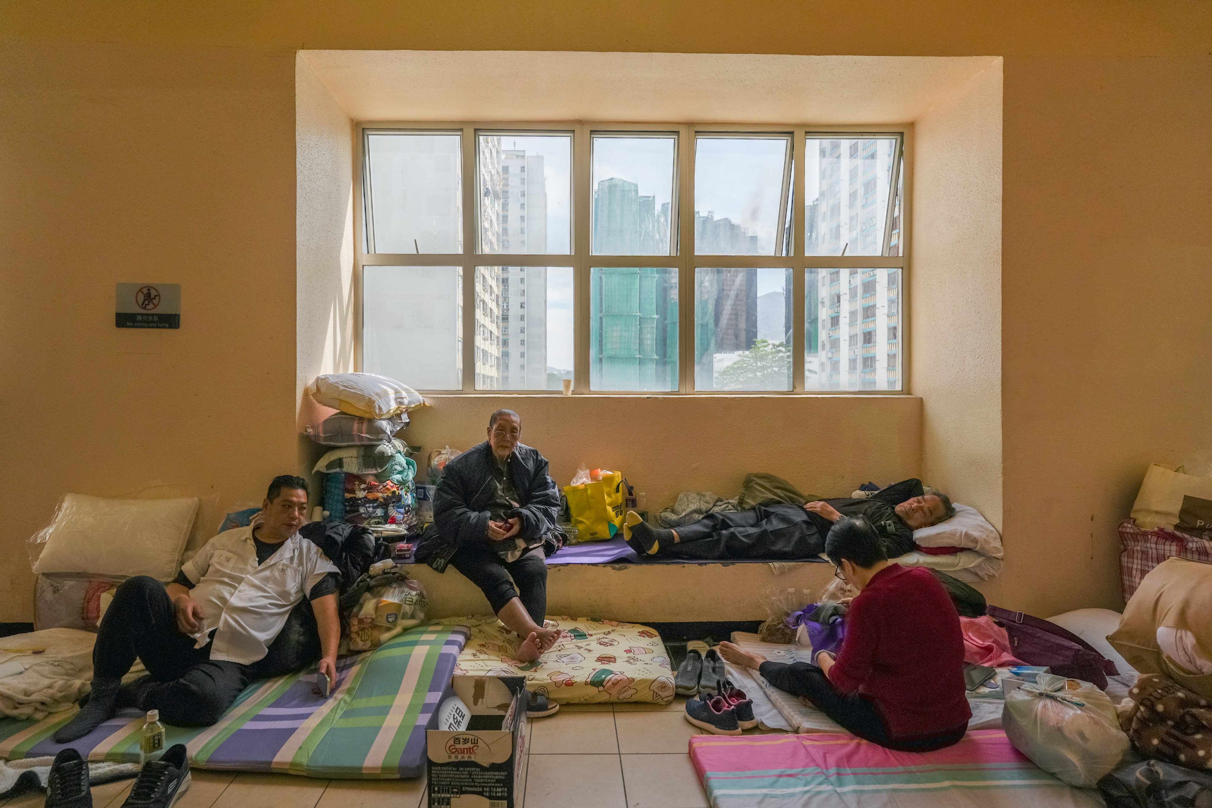 Residents take shelter at Kwong Fuk Commercial Centre on November 27 as the Tai Po fire burns in the background. Photo: Eugene Lee
