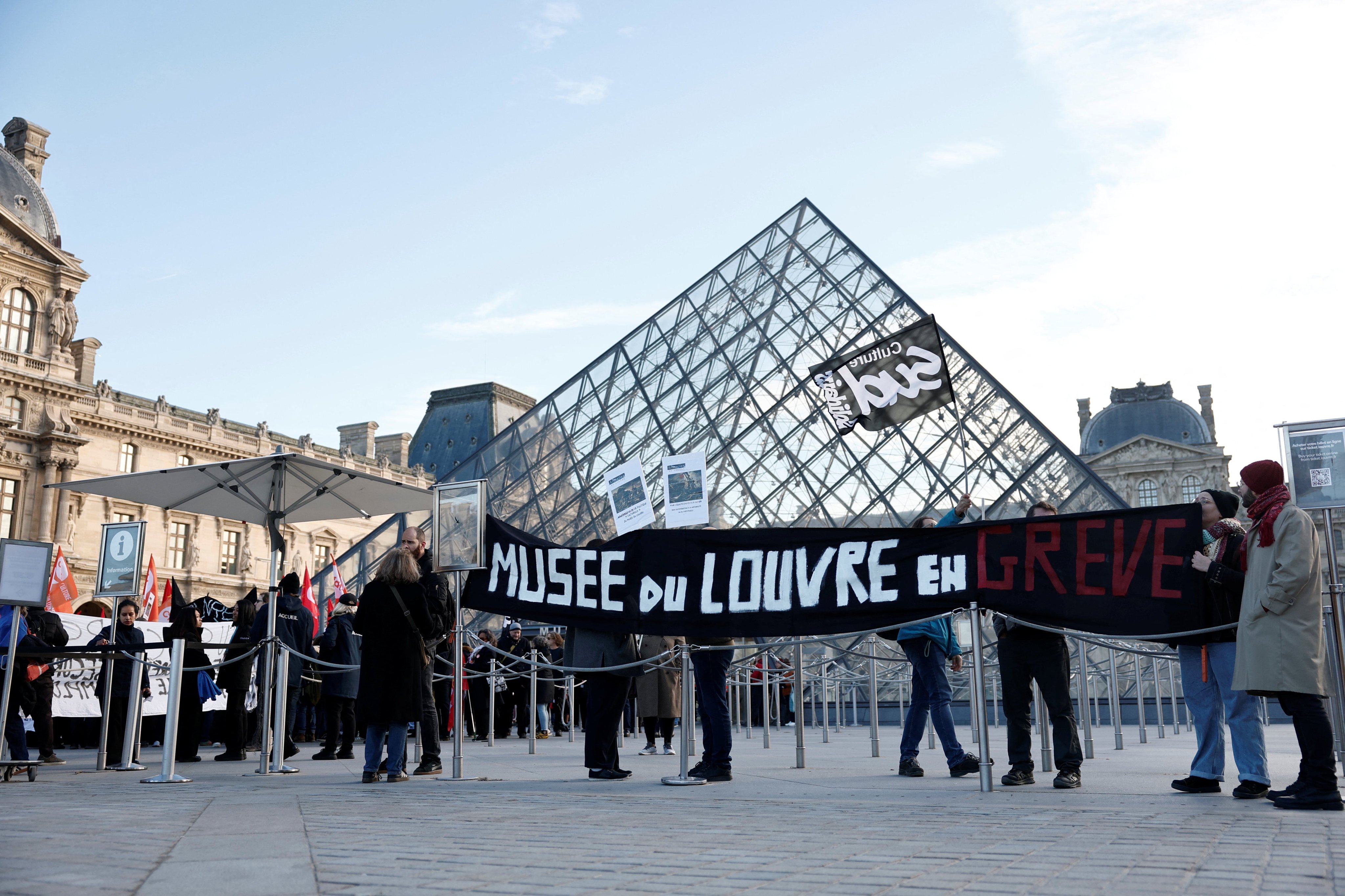 Louvre employees hold a banner reading “Louvre museum on strike” as they gather by the closed museum’s glass pyramid to protest working conditions on Monday. Photo: Reuters