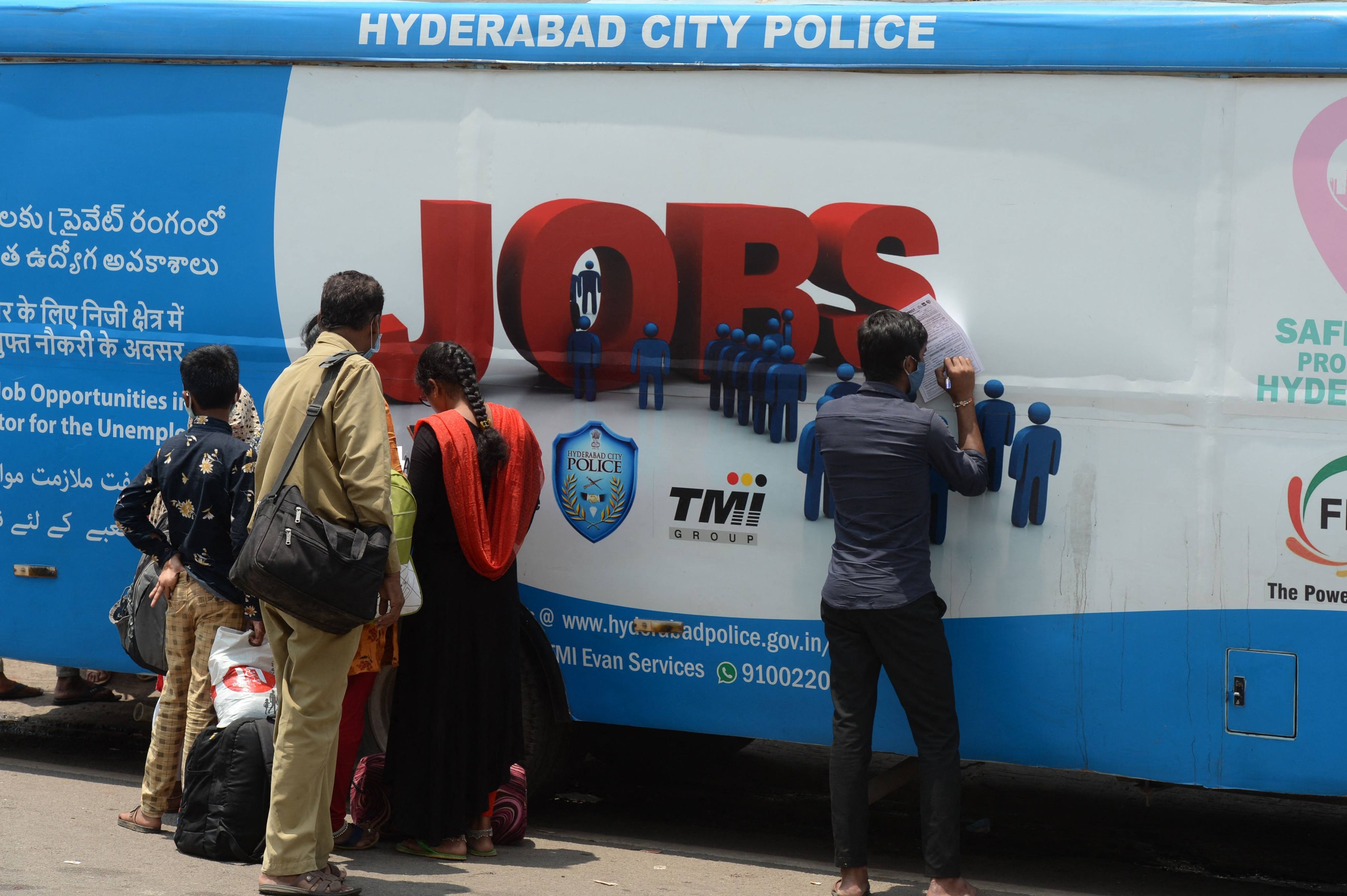 Unemployed youths fill application forms to access job openings outside an “employment van” in Hyderabad in 2021. Photo: AFP