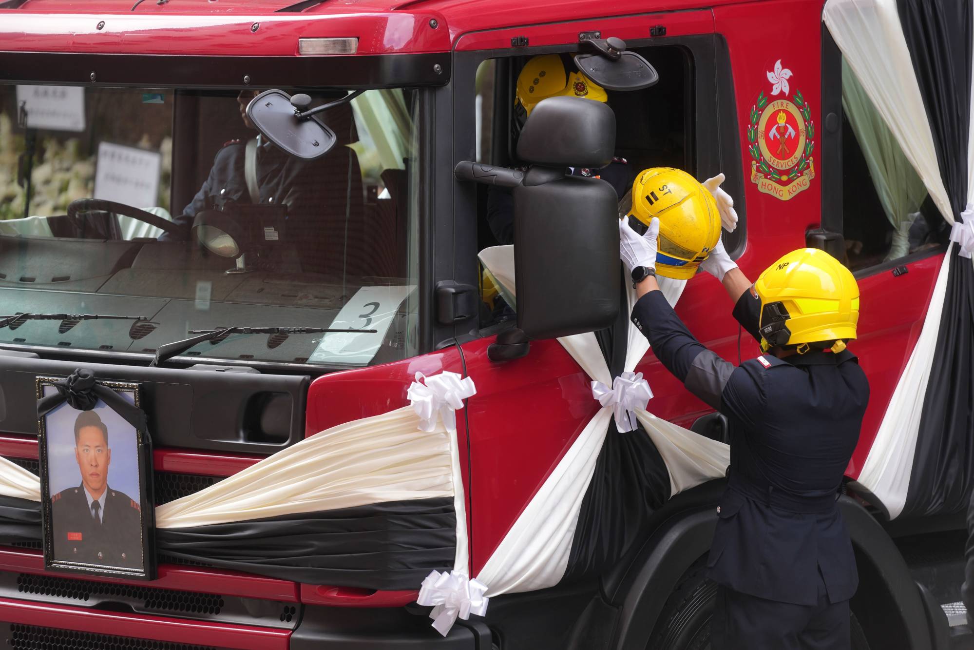 A firefighter receives the helmet of the late Ho Wai-ho in the hearse, a refitted fire truck. Photo: Elson Li A firefighter receives the helmet of the late Ho Wai-ho in the hearse, a refitted fire truck. Photo: Elson Li