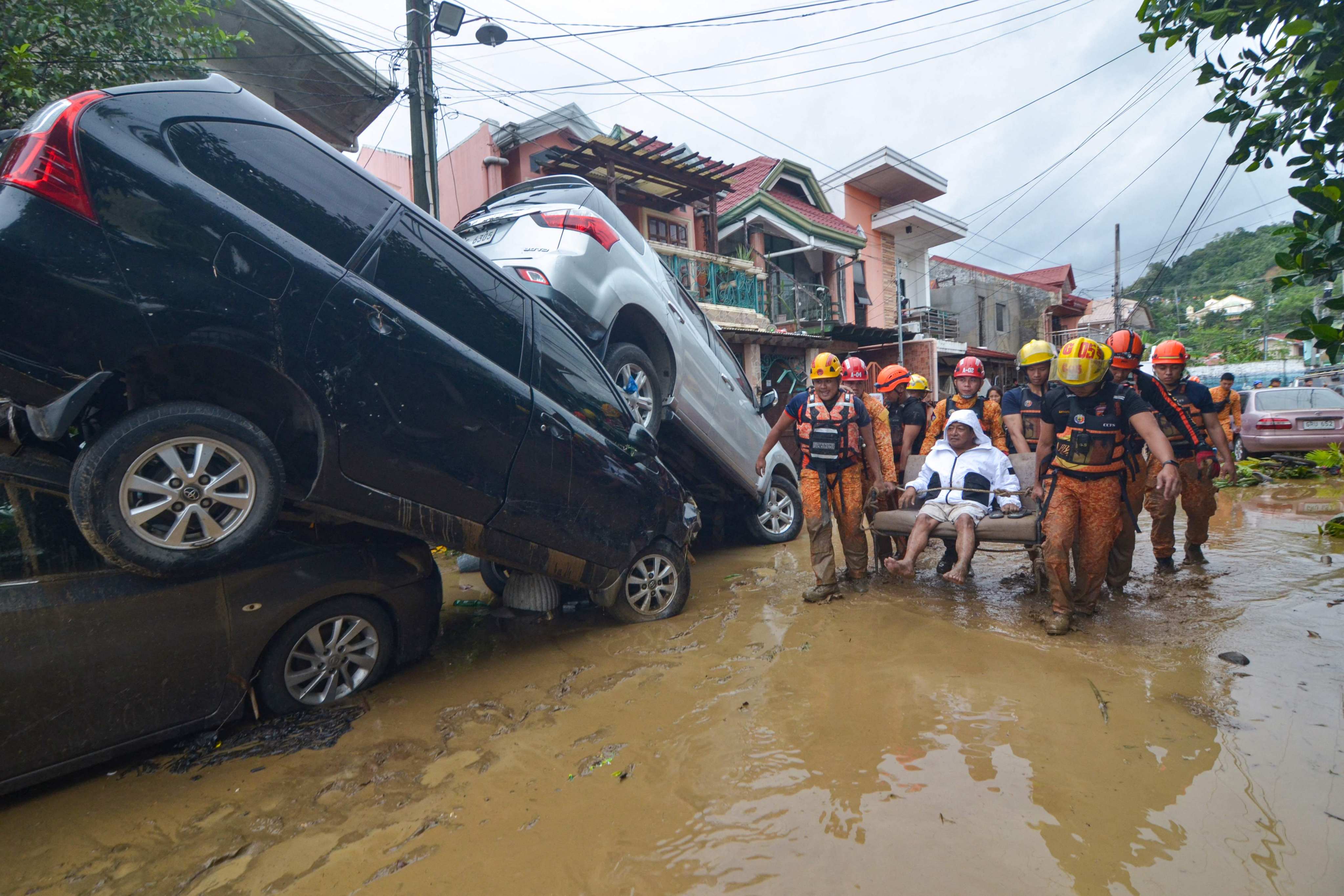 Rescuers carry a resident of Cebu City, the Philippines, past cars swept away in floods brought by Typhoon Kalmaegi on November 4. Photo: AFP