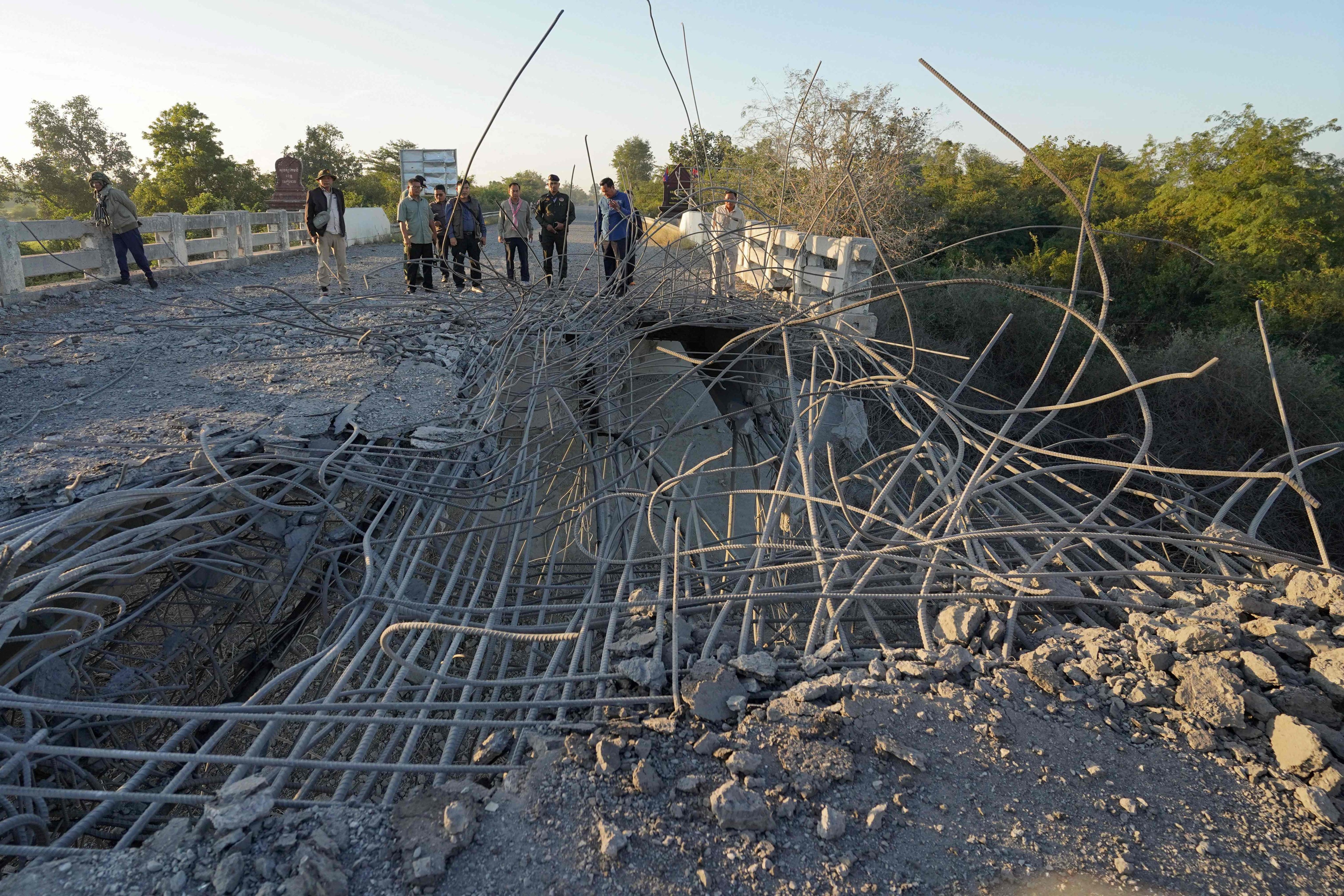 People inspect a damaged bridge after Thailand carried out air strikes in an area between Cambodia’s Oddar Meanchey and Siem Reap provinces on Saturday. Photo: AFP