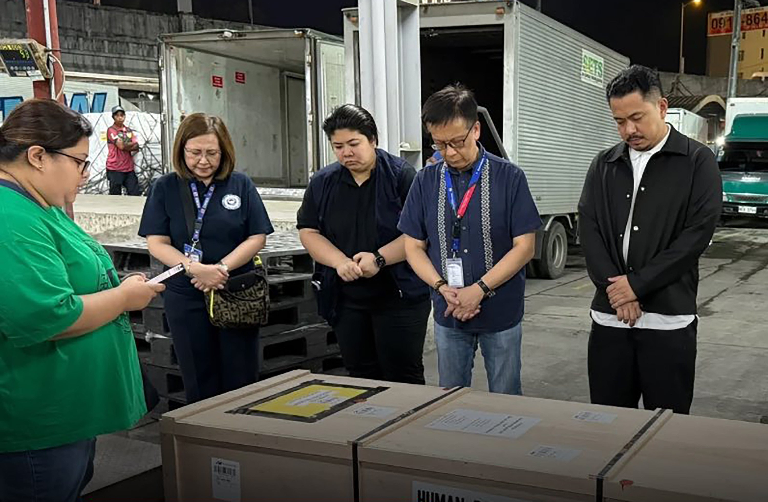 Secretary for Migrant Workers Hans Leo Cacdac (second from right) and others bow their heads next to the coffin of Maryan Pascual Esteban. Photo: Handout