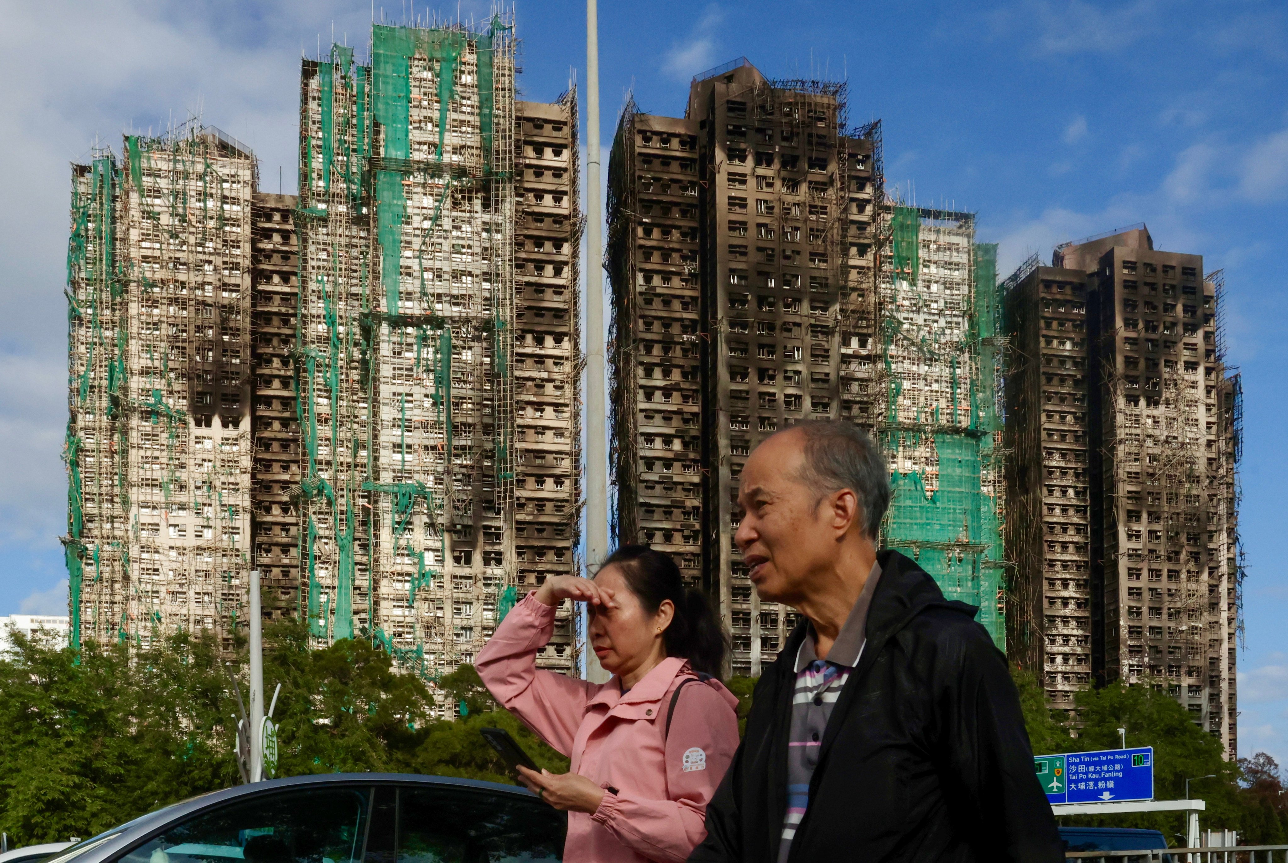 People walk past Wang Fuk Court in Tai Po, on December 20, weeks after a deadly fire burned the community and at least claimed 161 lives. Photo: Jonathan Wong