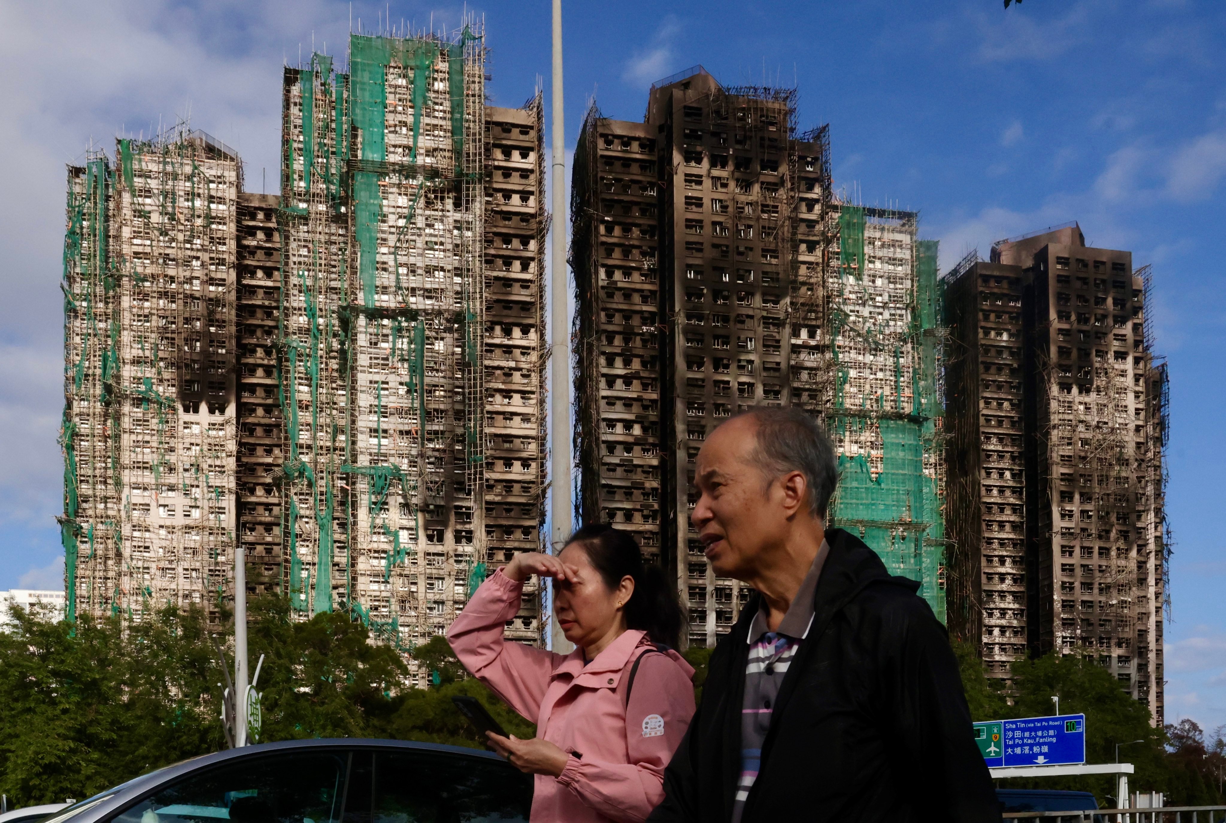 People walk past the blackened blocks of Wang Fuk Court in Tai Po on December 20. Photo: Jonathan Wong