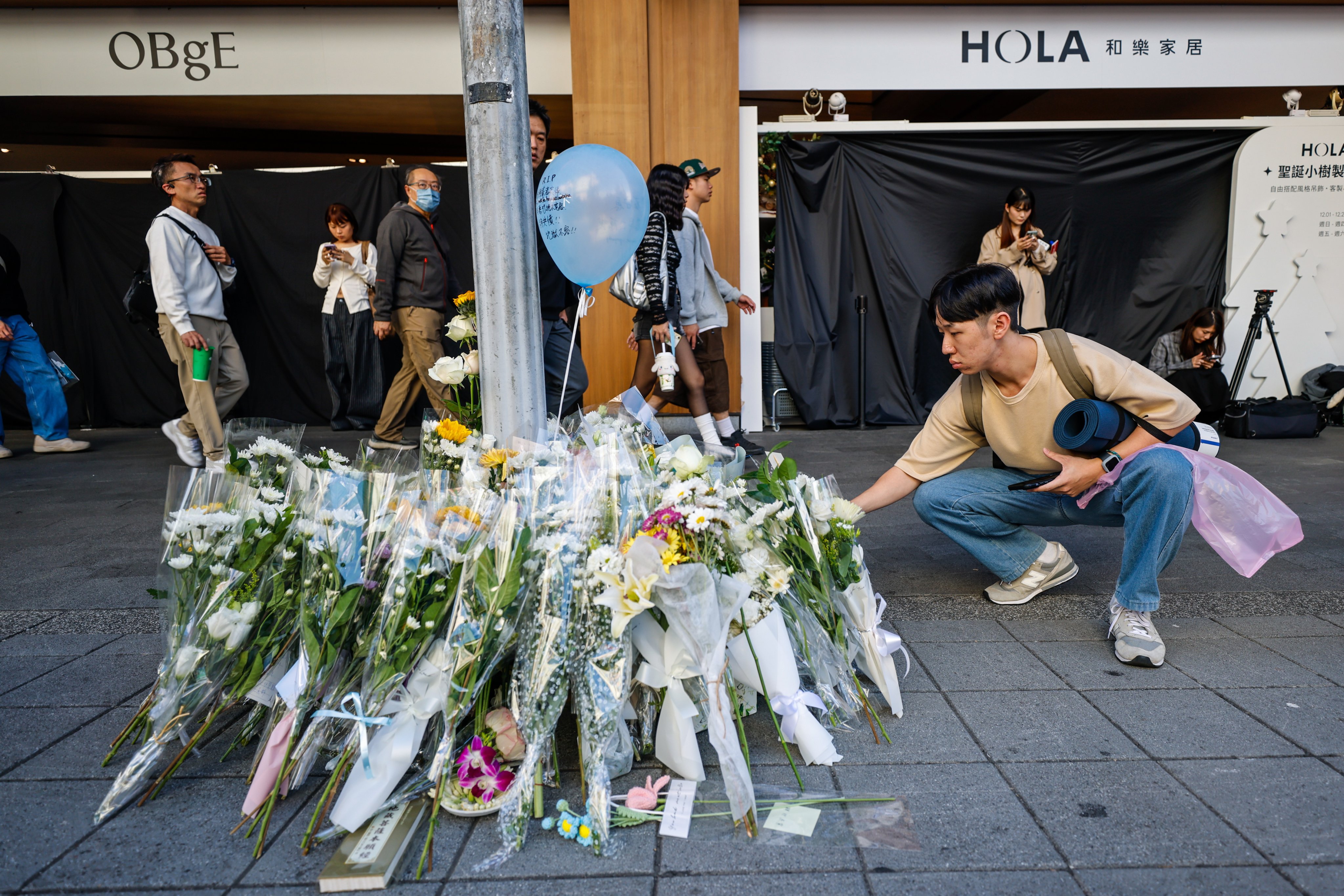 A passer-by places flowers at a make-shift shrine for the victims inside a Taipei shopping mall on December 20, the day after a deadly knife rampage shook Taiwan. Photo: EPA