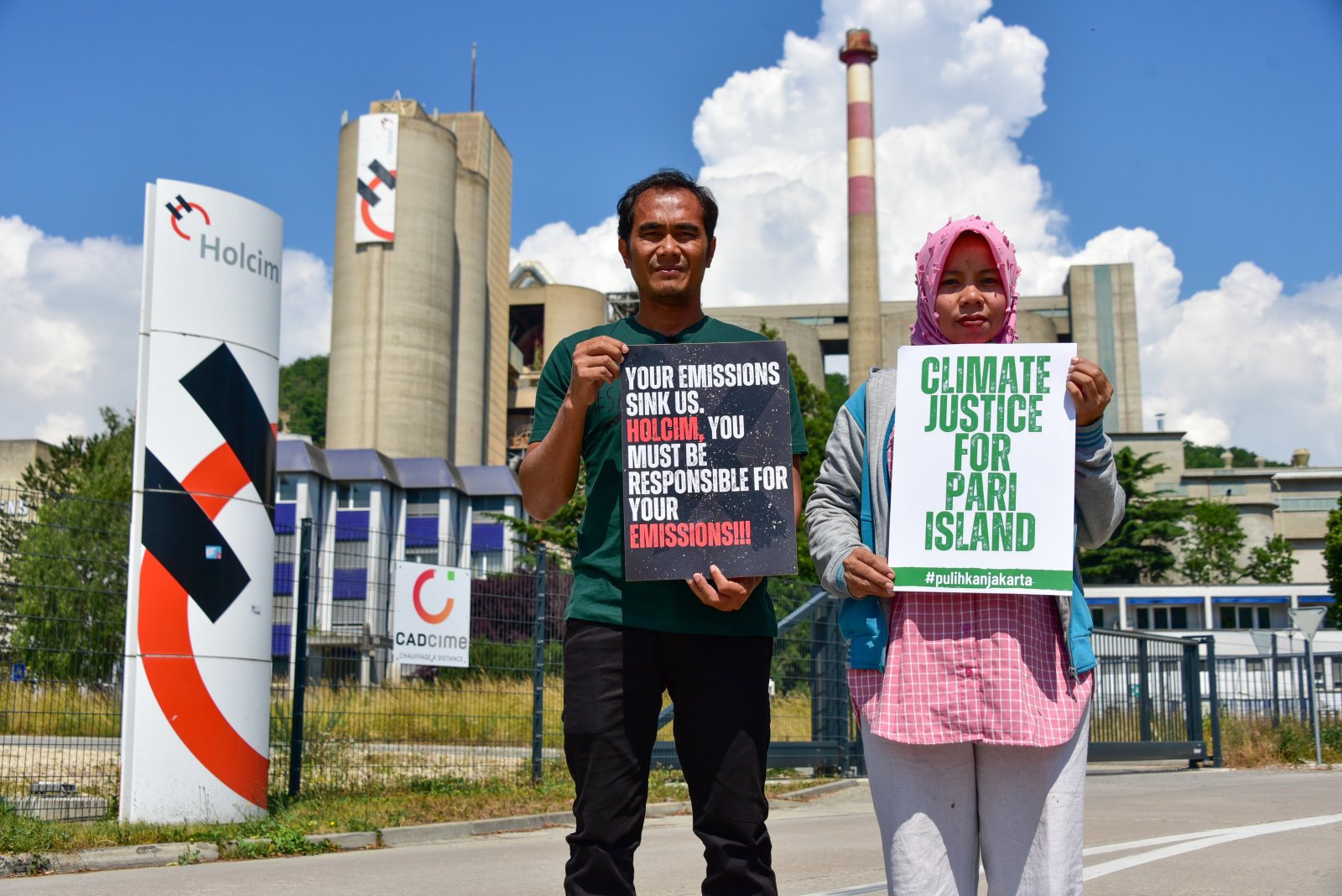 Edi Mulyono and Asmania, two of four plaintiffs who have filed a lawsuit against cement company Holcim for its role in climate change, stand in front of Holcim’s Eclepens cement plant in 2023. Photo: Lorenz Kumme/HEKS/EPER