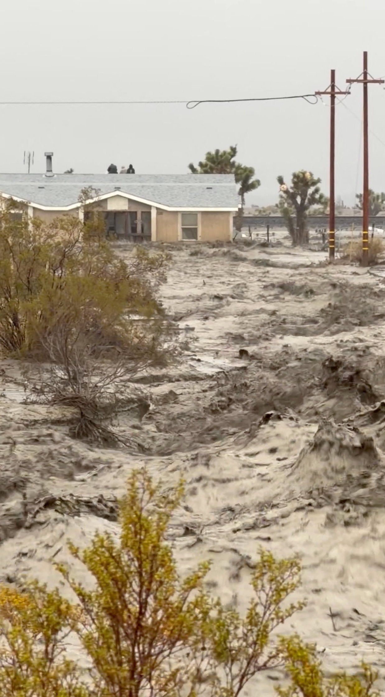 People sit on the roof of a building, stranded during floods in San Bernardino County in California on Christmas Eve, in this screengrab from a social media video. Photo: Timothy and the Machine Music/Facebook/via Reuters