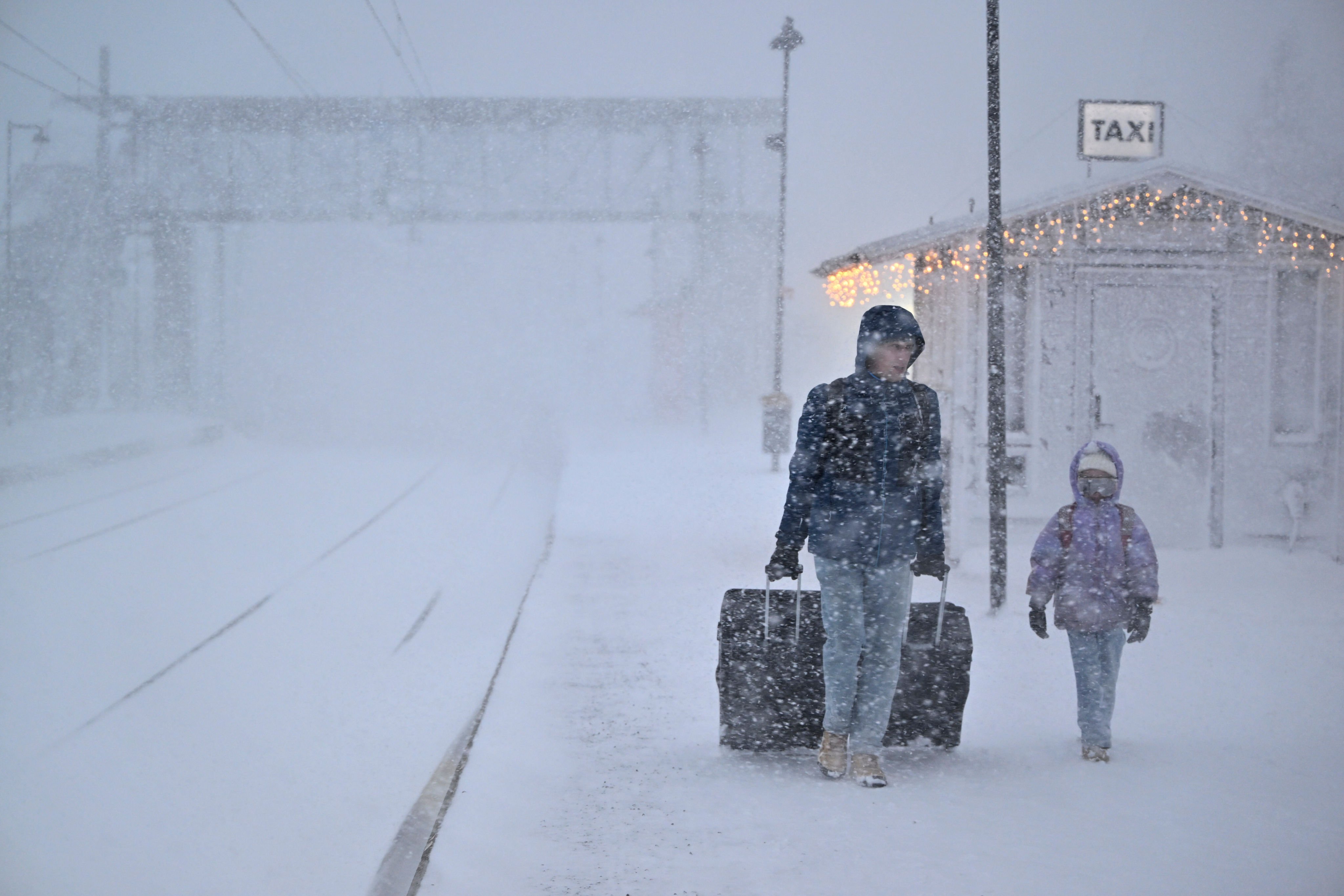 People walk in heavy snow as departures are cancelled at the train station in Are, Sweden on Saturday. Photo: TT News Agency via AP