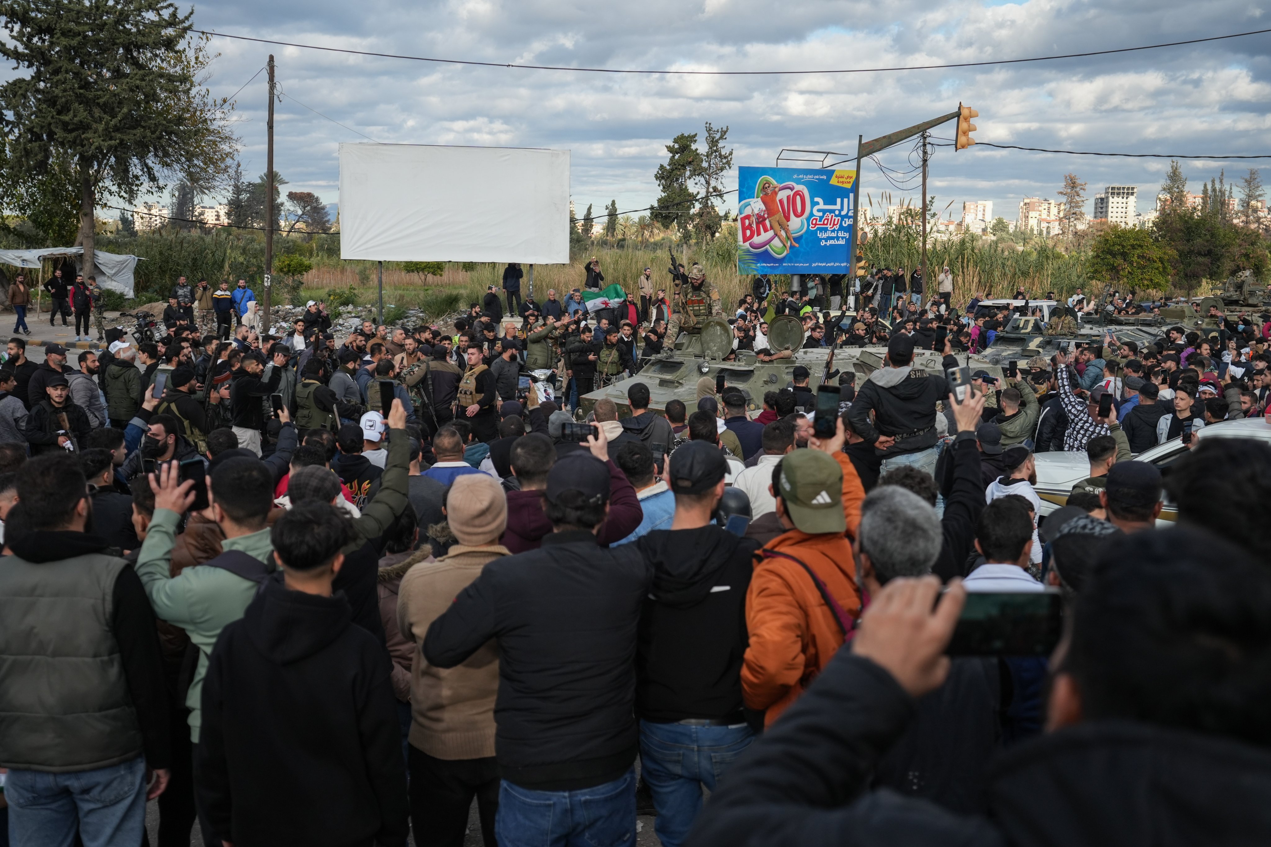 A crowd looks on as security forces are deployed after clashes erupted during a protest by members of the Alawite community in the city of Latakia, Syria on Sunday. Photo: EPA