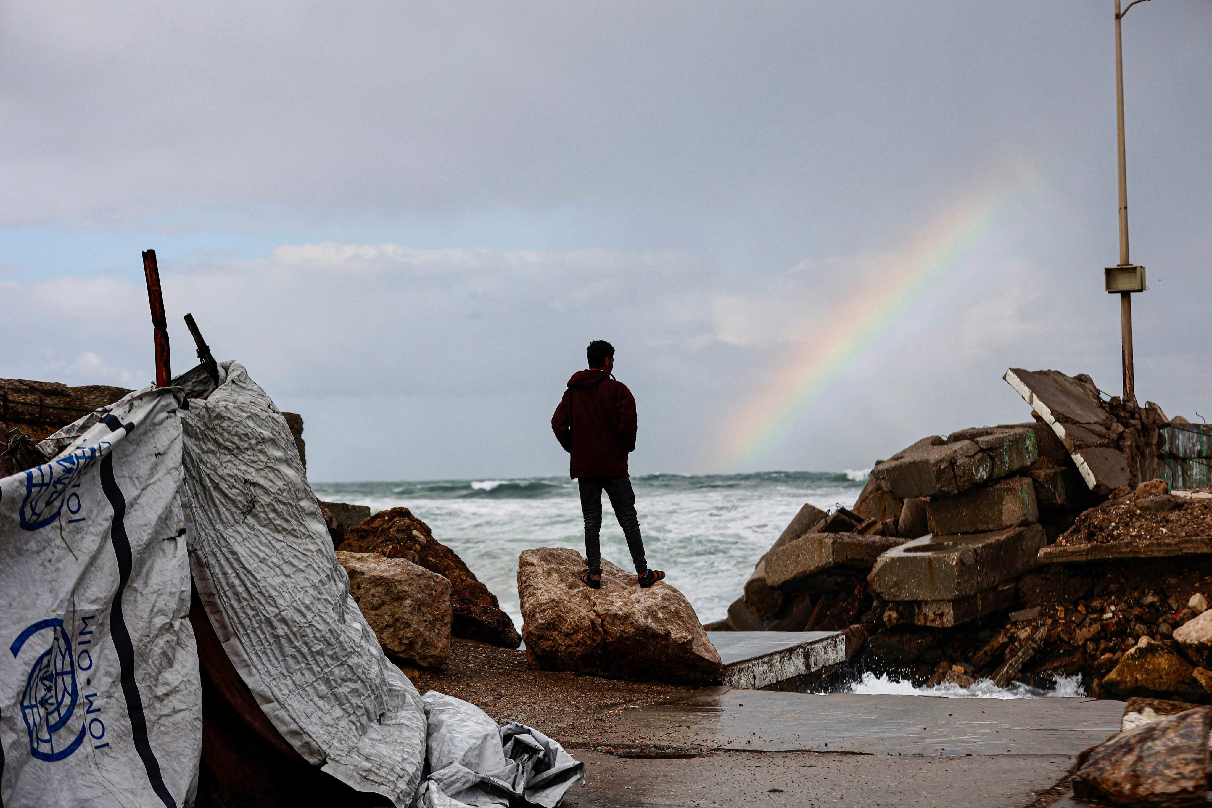 A displaced Palestinian man looks at a rainbow out at sea in Gaza on Sunday. Photo: AFP