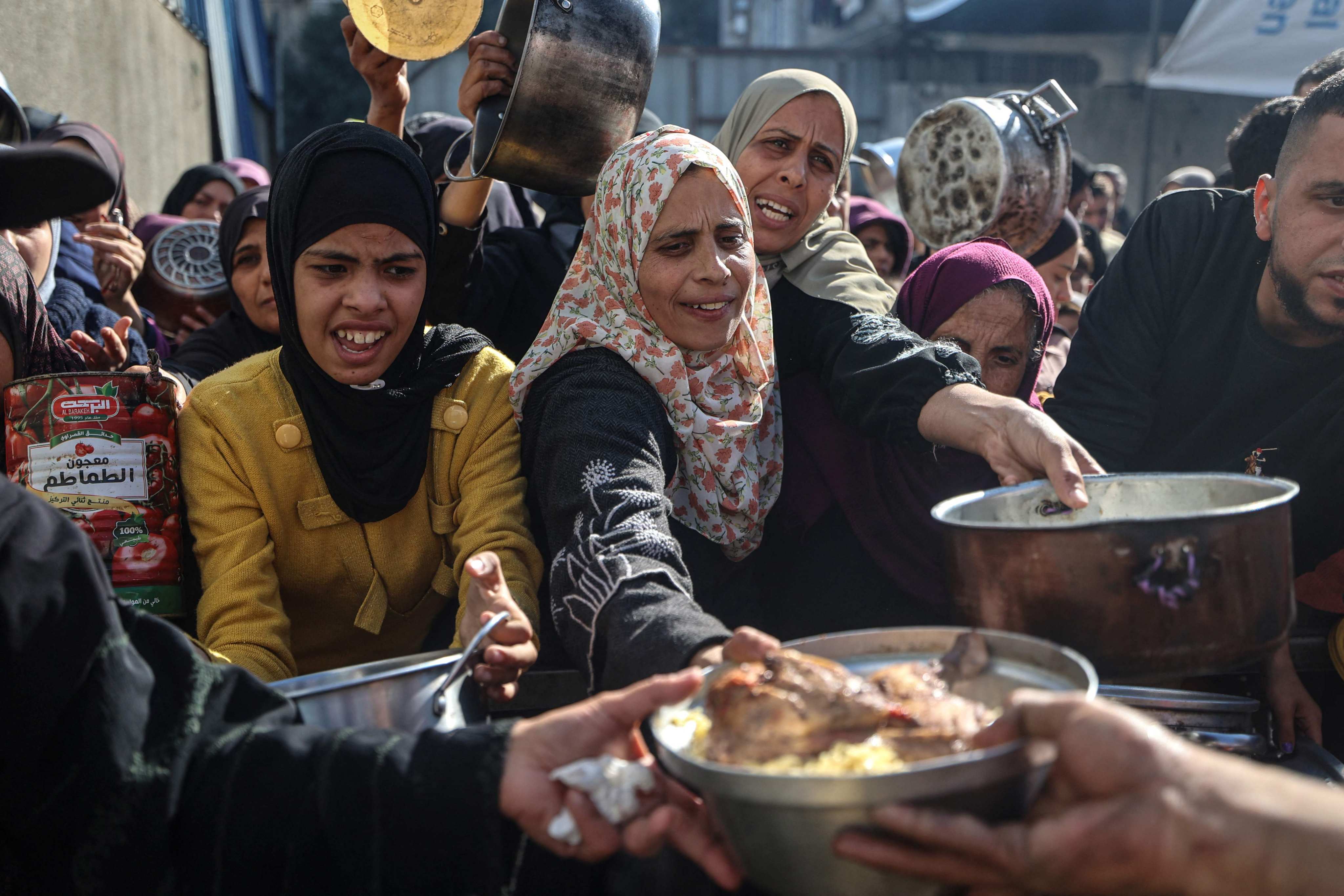 Displaced Palestinians gather for food at a charity kitchen in central Gaza on December 20. Israel will suspend over two dozen aid groups for not meeting new vetting rules in Gaza. Photo: AFP