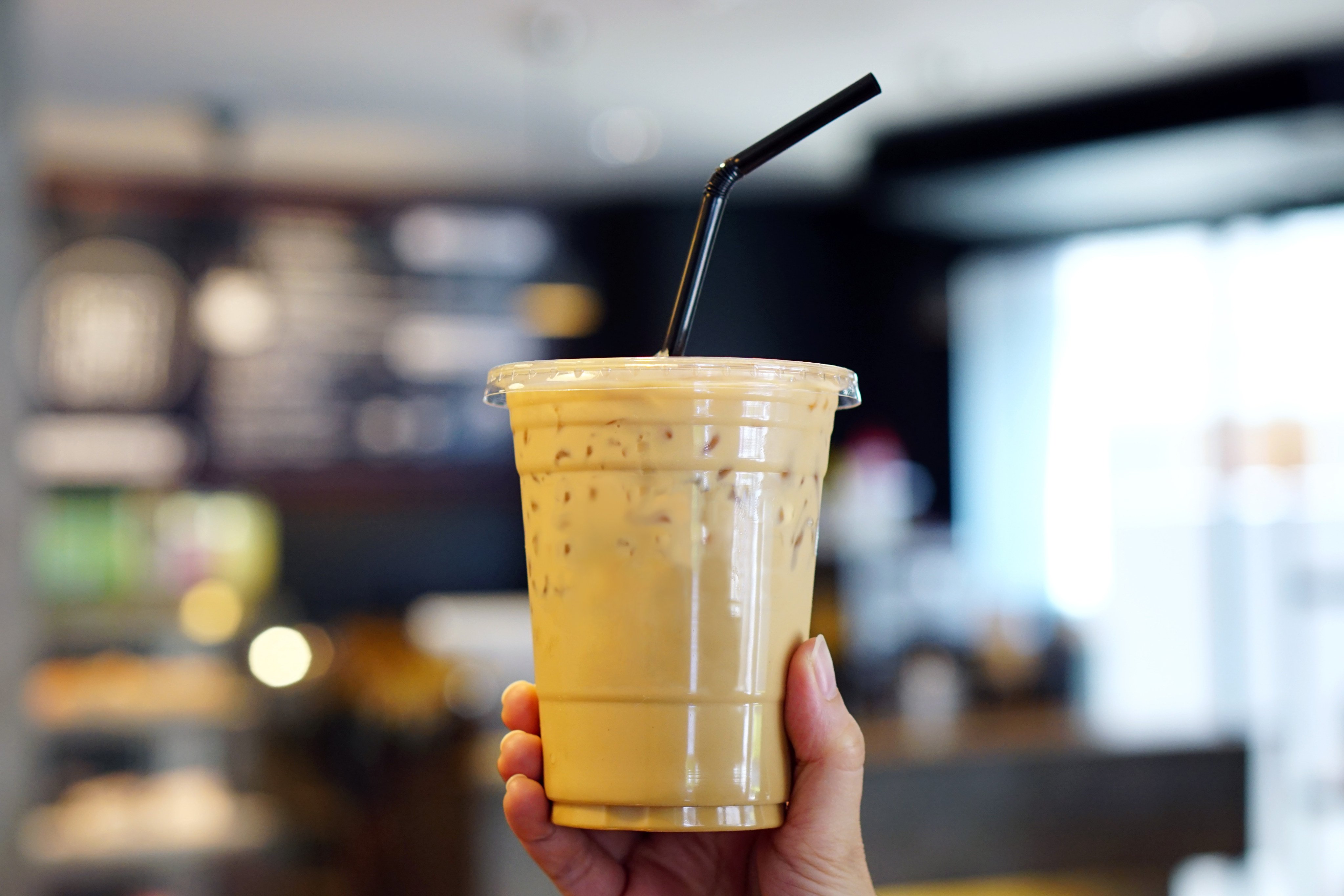 A woman holding plastic cup of iced coffee with milk. Photo: Shutterstock