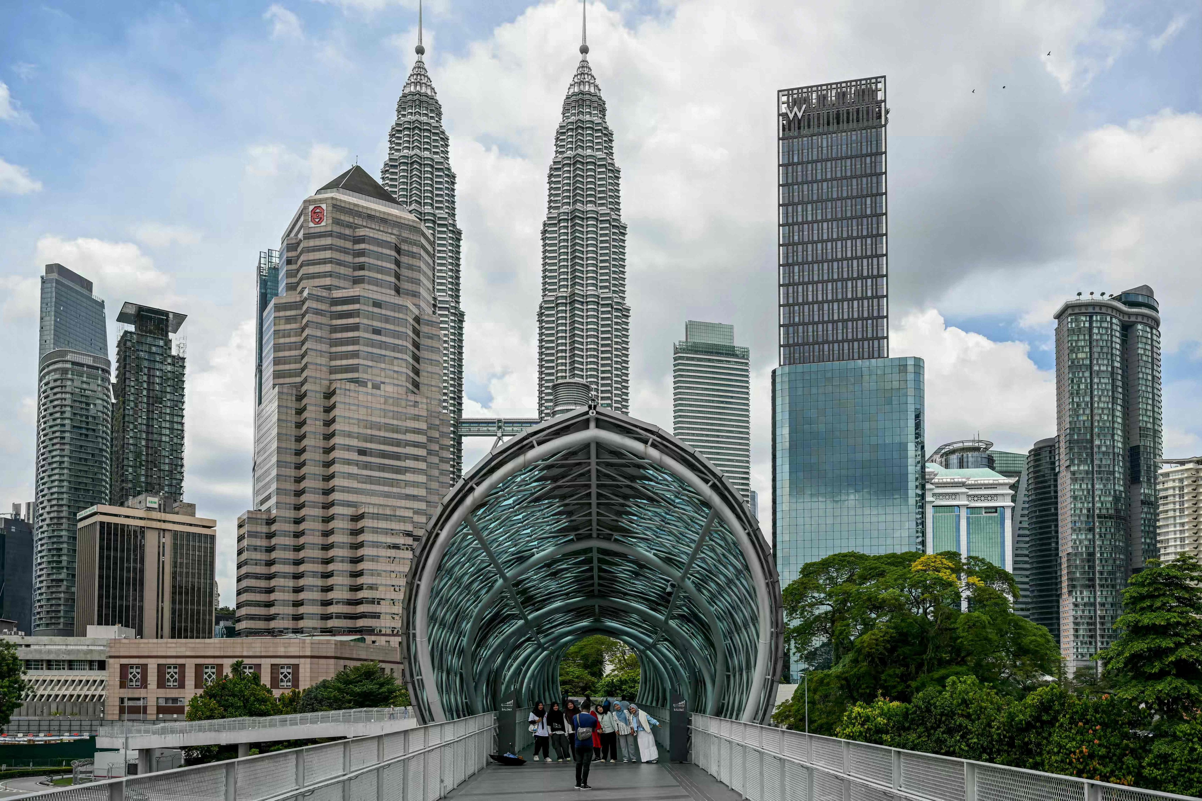 Tourists take pictures with Malaysia’s Petronas Twin Towers in the background in Kuala Lumpur. The country aims to attract 47 million international visitors during the Visit Malaysia 2026 campaign. Photo: AFP