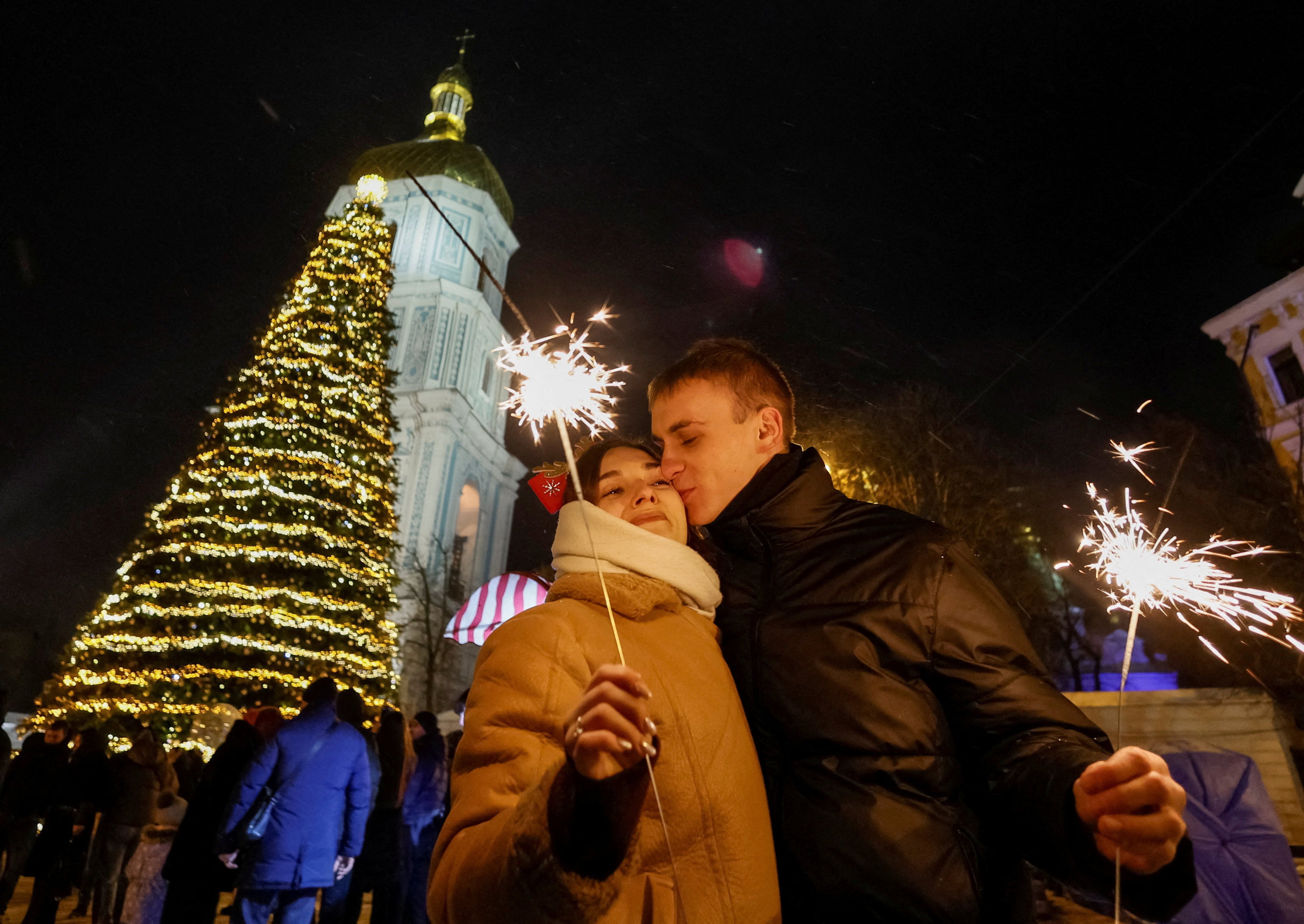 A couple kiss next to a Christmas tree in Kyiv, Ukraine, during celebrations before a curfew on December 31. Photo: Reuters