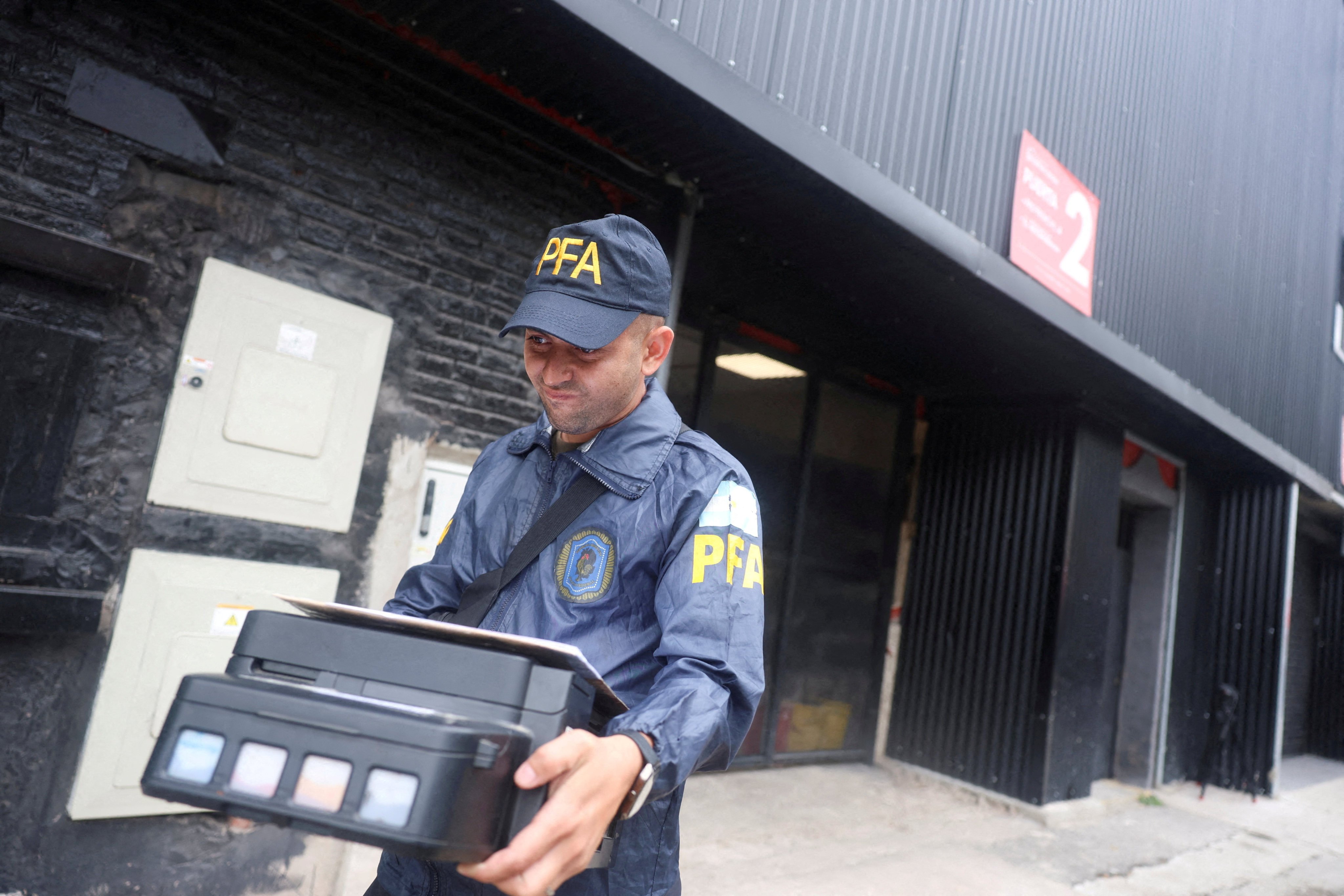 A member of the Argentine Federal Police walks after seizing a printer from the Claudio Chiqui Tapia stadium in Buenos Aires, which belongs to the soccer team Barracas Central, during a raid on December 9. Photo: Reuters