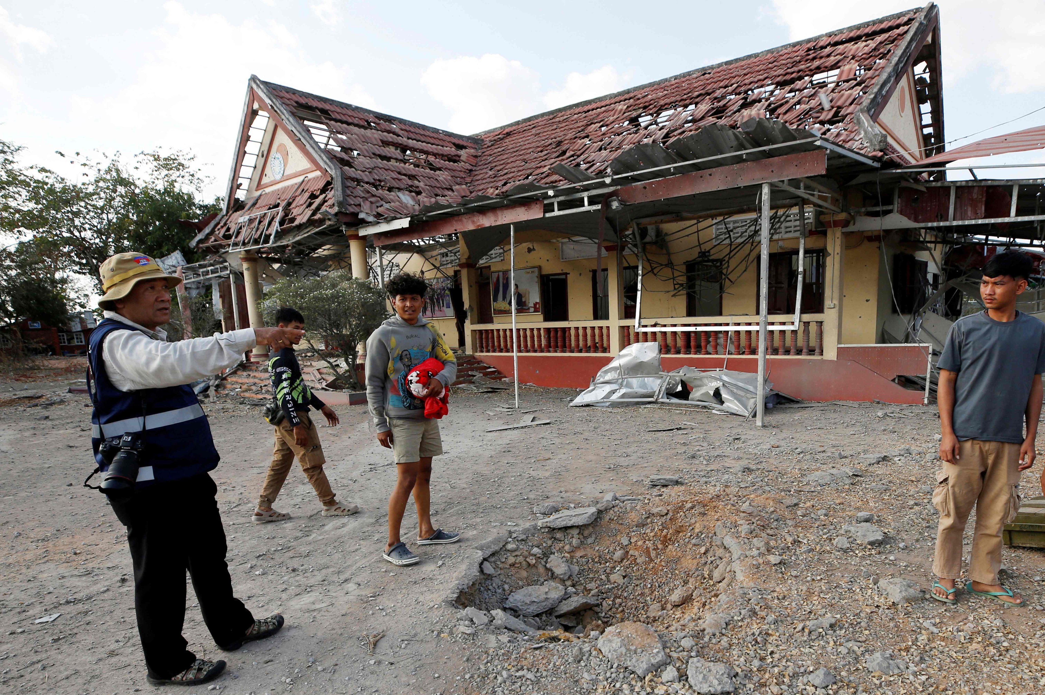 People stand beside a crater in front of a damaged police station following clashes between Cambodian and Thai soldiers in Banteay Meanchey province, Cambodia on Saturday. Photo: AFP