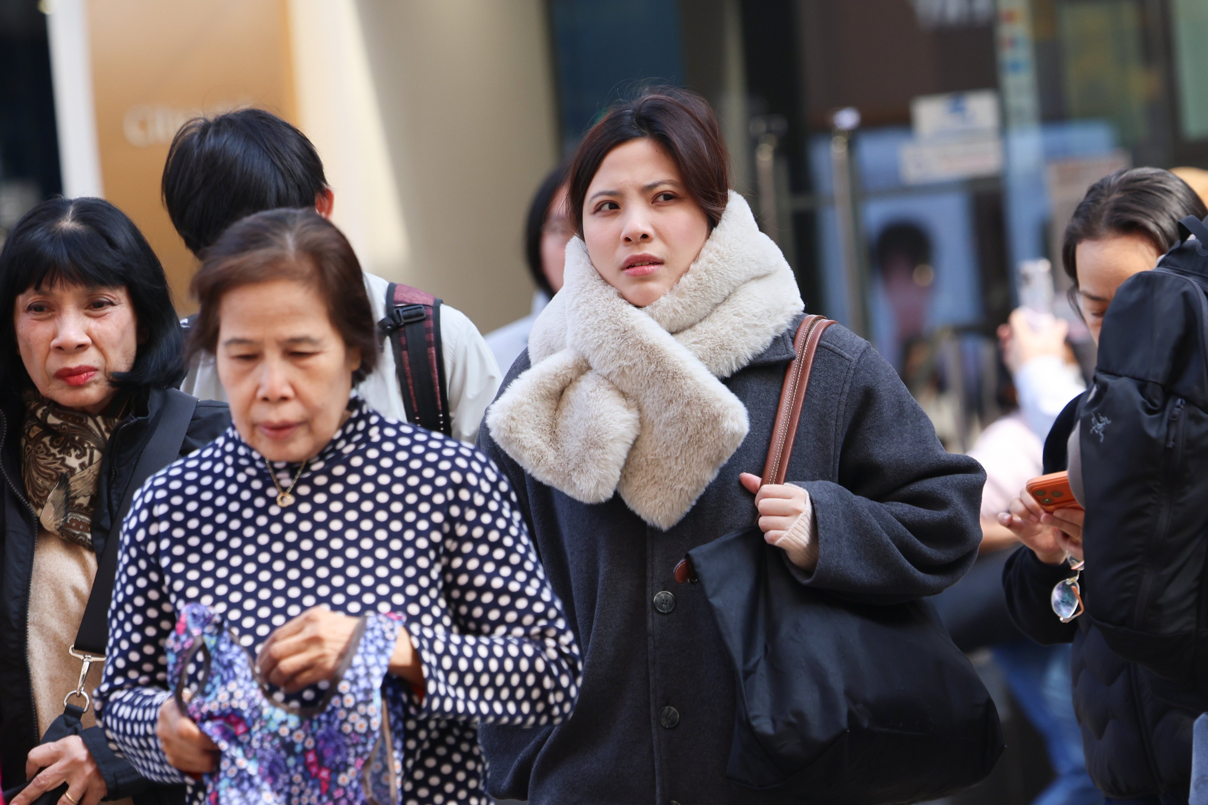 People walk past at Tsim Sha Tsui under the cold weather.  A Cold Weather Warning and a Strong Monsoon Signal are now in force. The temperature in Hong Kong has generally dropped to around 12 degrees this morning in the urban areas, and a further two to three degrees lower in the New Territories. Photo: Jelly Tse