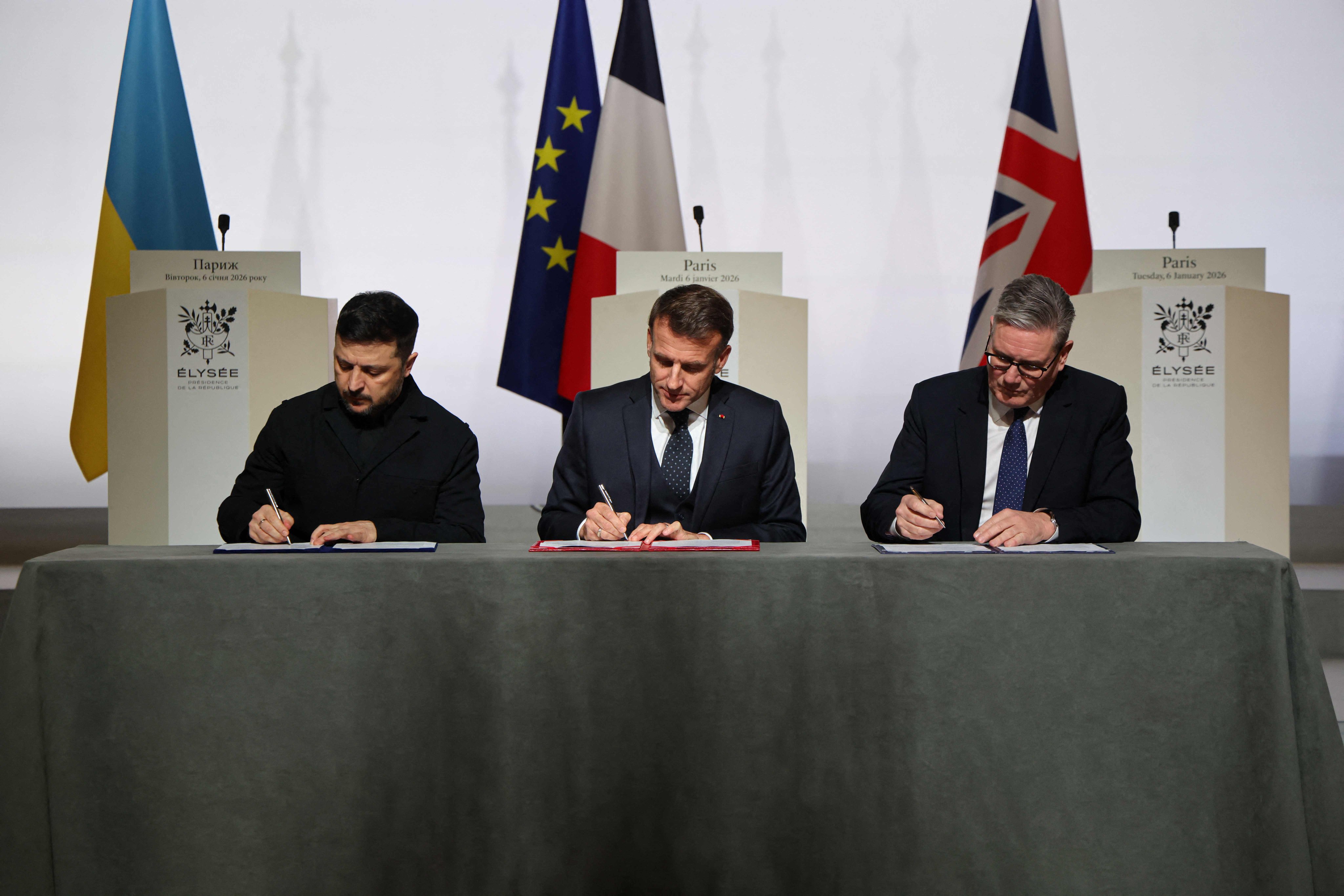 Ukraine’s President Volodymyr Zelensky signs a declaration  of intent along with France’s President Emmanuel Macron and Britain’s Prime Minister Keir Starmer. Photo: AFP