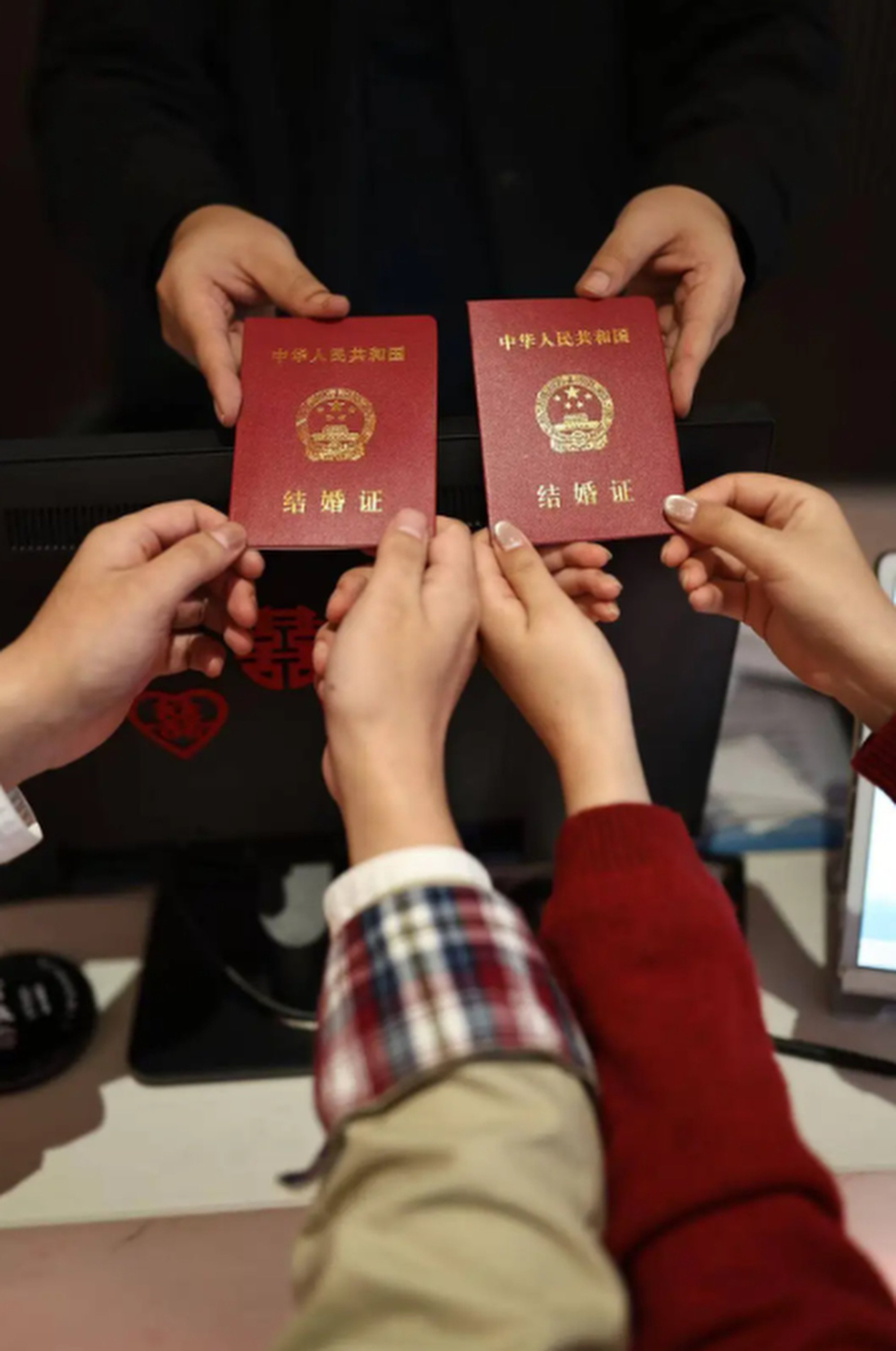 The happy couple, who dated for 10 years, display their marriage passbooks. Photo: QQ.com