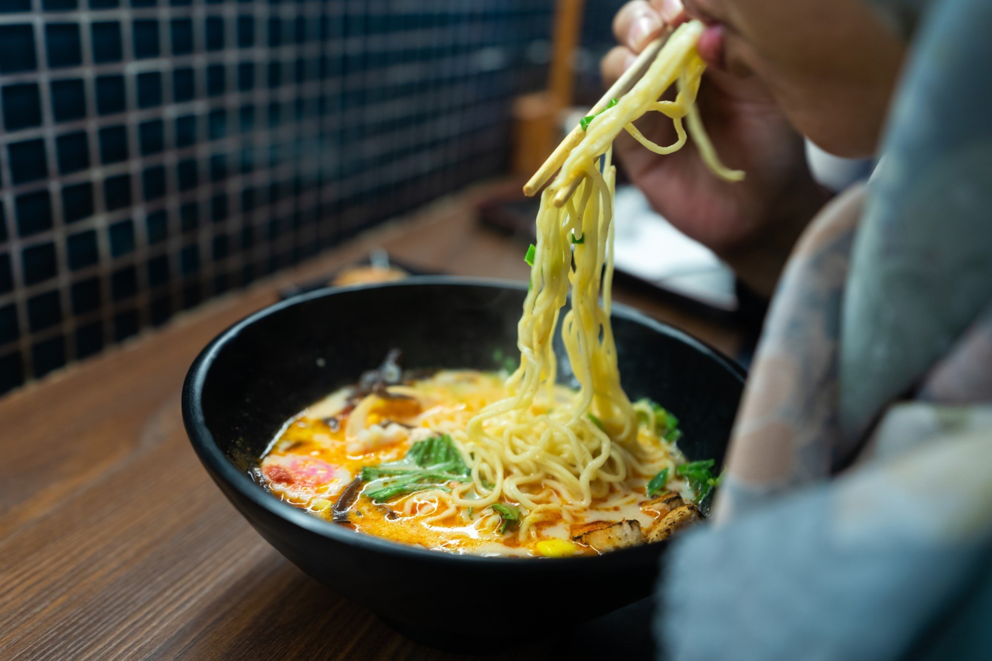 A woman tucks into a bowl of ramen noodles in a Japanese eatery. Photo: Shutterstock