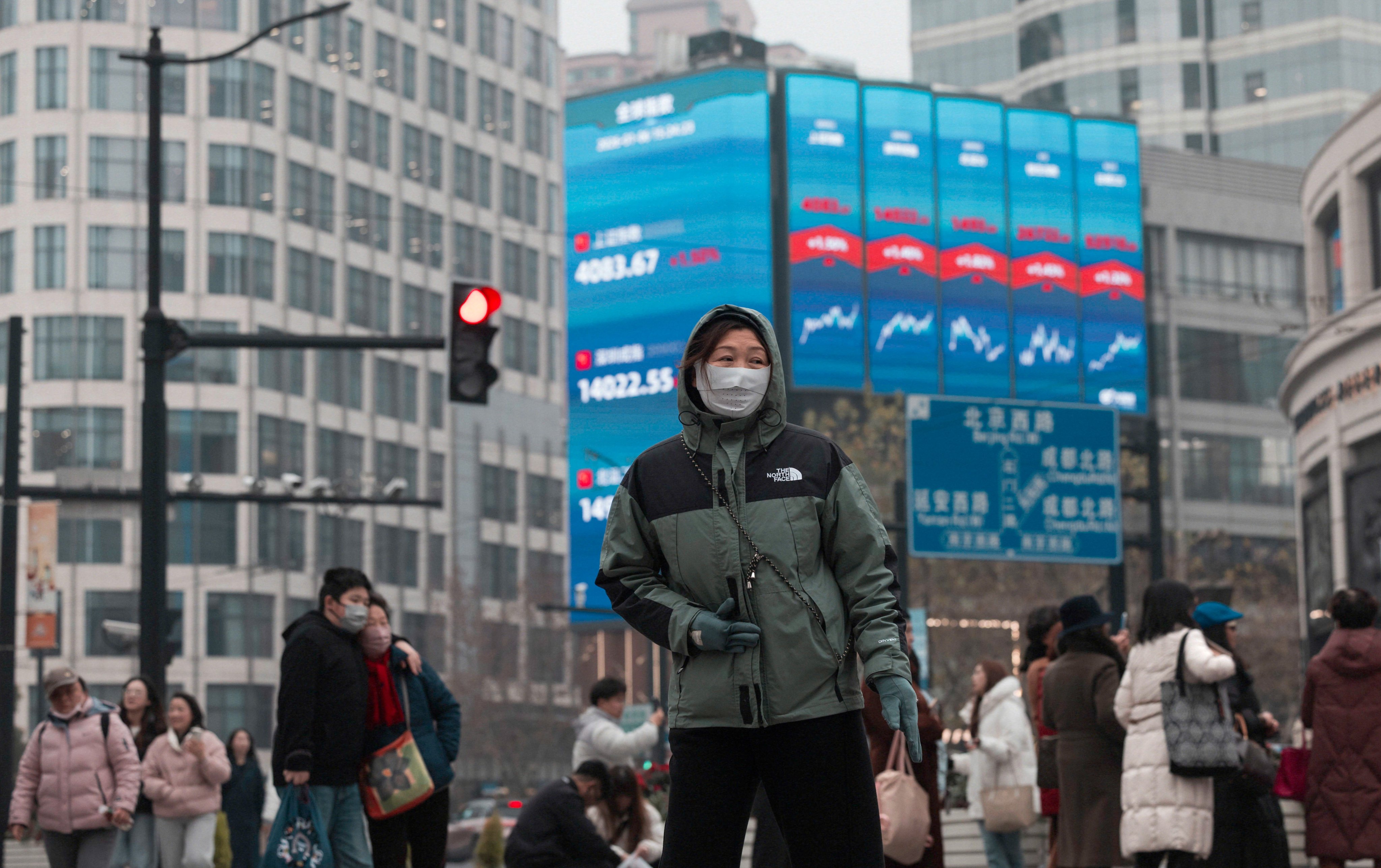 People walk below a large screen displaying the latest stock exchange and economic data in Shanghai on January 6. Photo: EPA