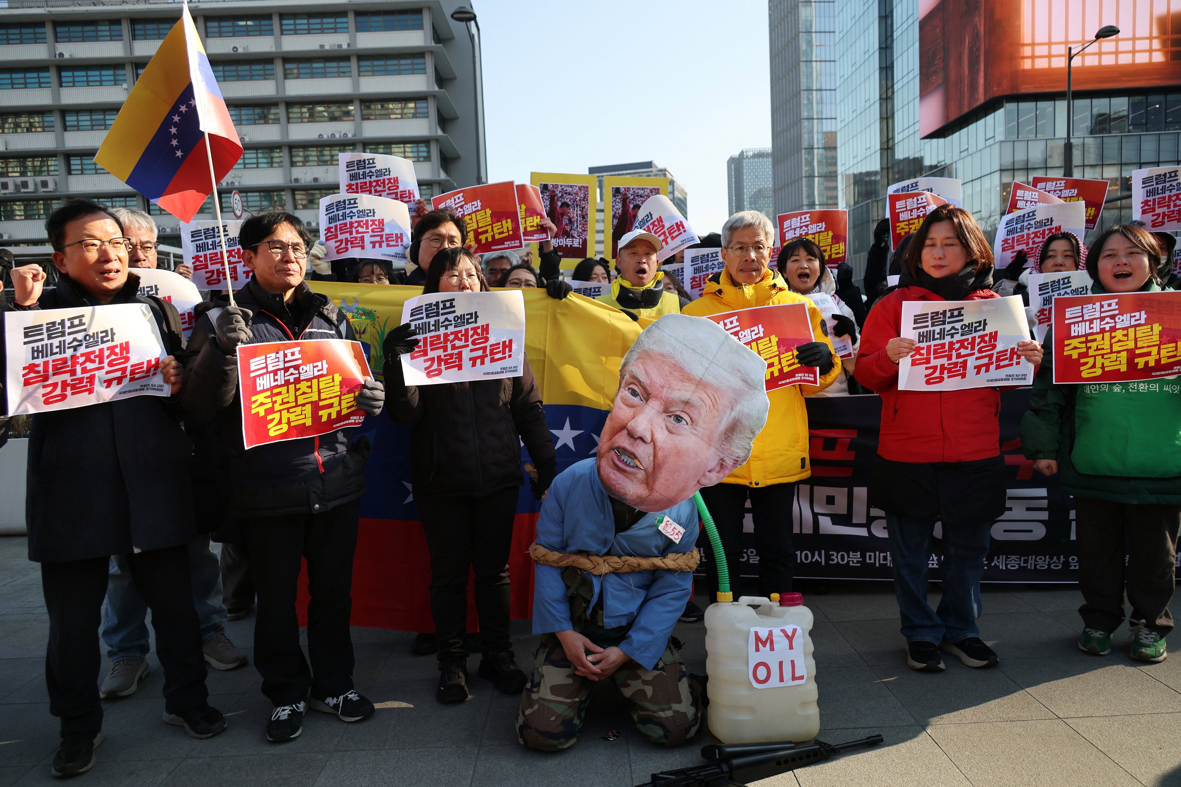 An activist, wearing a mask depicting US President Donald Trump kneels next to a container, as people take part in an anti-US rally in Seoul on Monday. Photo: Reuters
