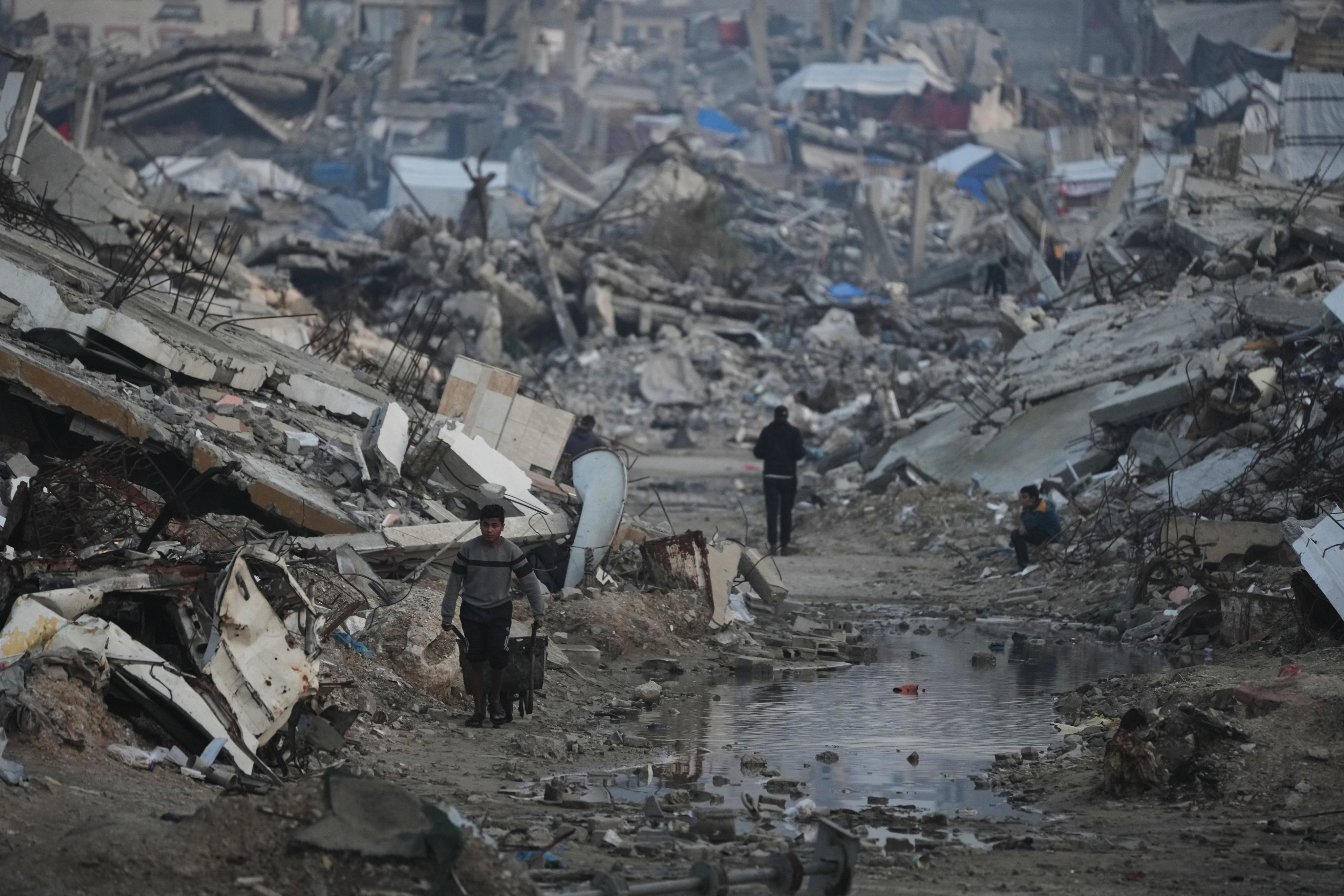 Palestinians walk amid buildings destroyed by Israeli air and ground operations in Gaza City. Photo: AP
