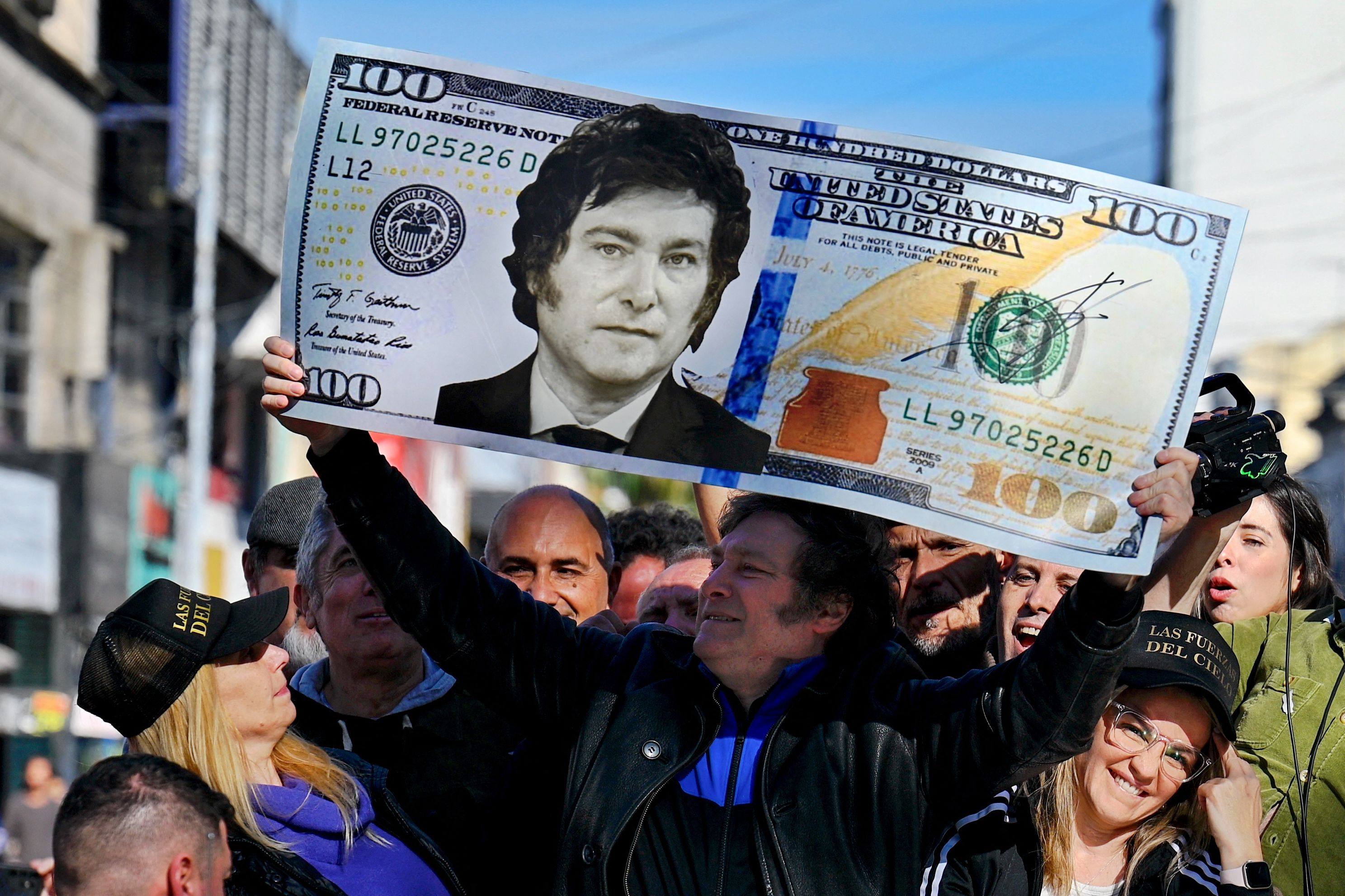 Javier Milei holds a giant 100-dollar bill with his face painted on it during a campaign rally in Argentina in September 2023. Photo: AFP
