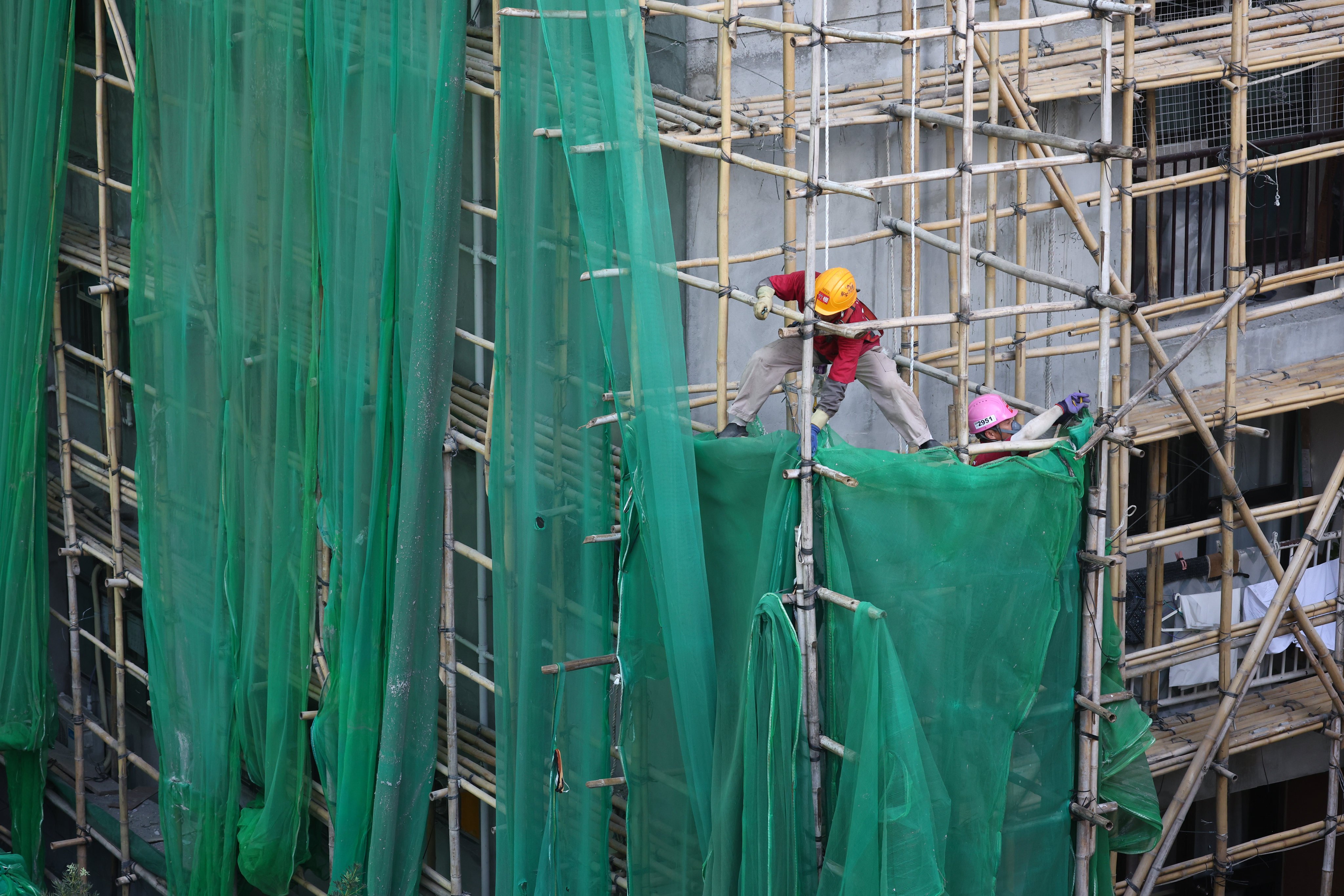 Workers remove scaffolding nets from a building in Hong Kong. Photo: Dickson Lee