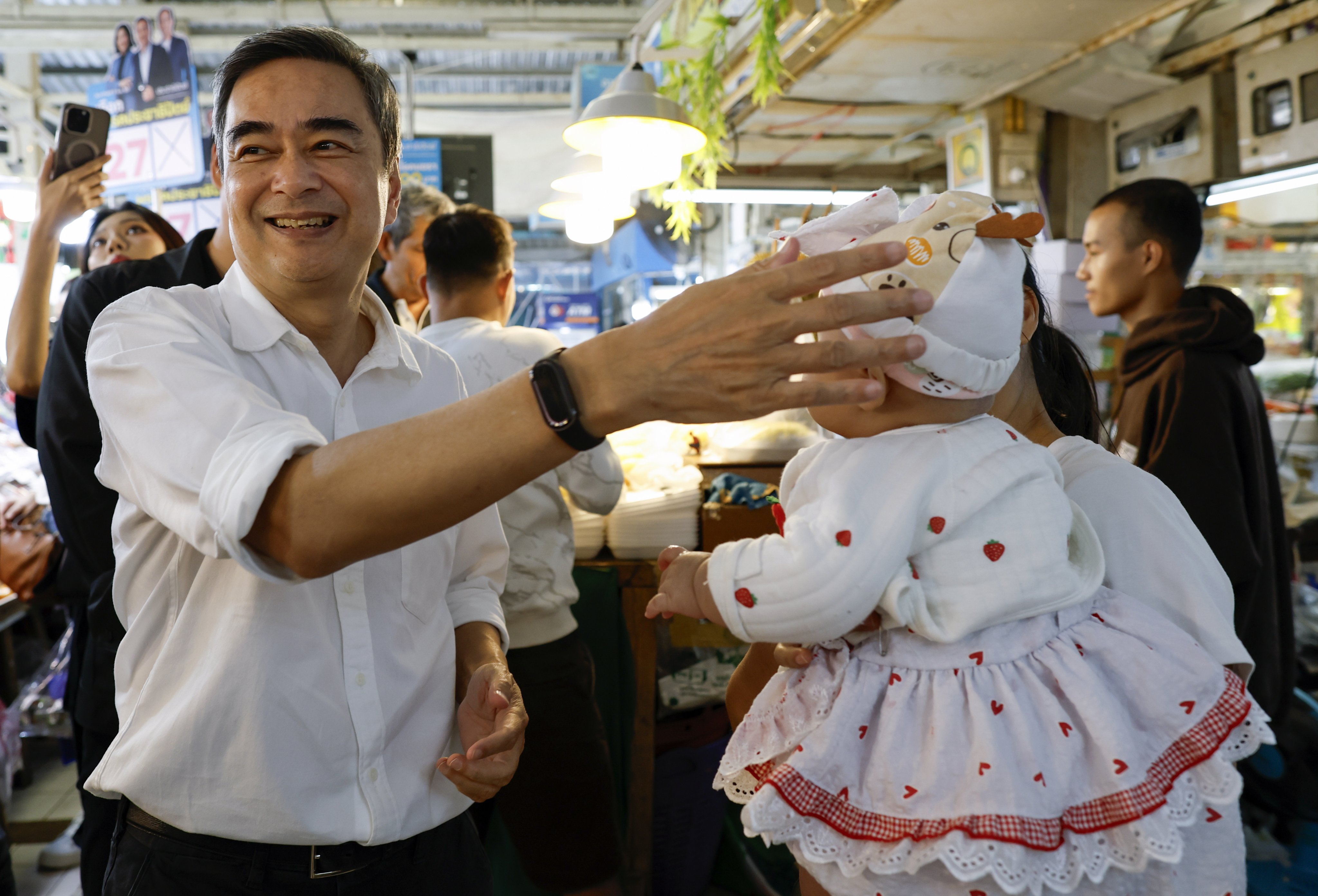 Abhisit Vejjajiva, leader of Thailand’s Democrat Party, greets a woman and her baby during an election campaign event in Bangkok on Saturday. Photo: EPA