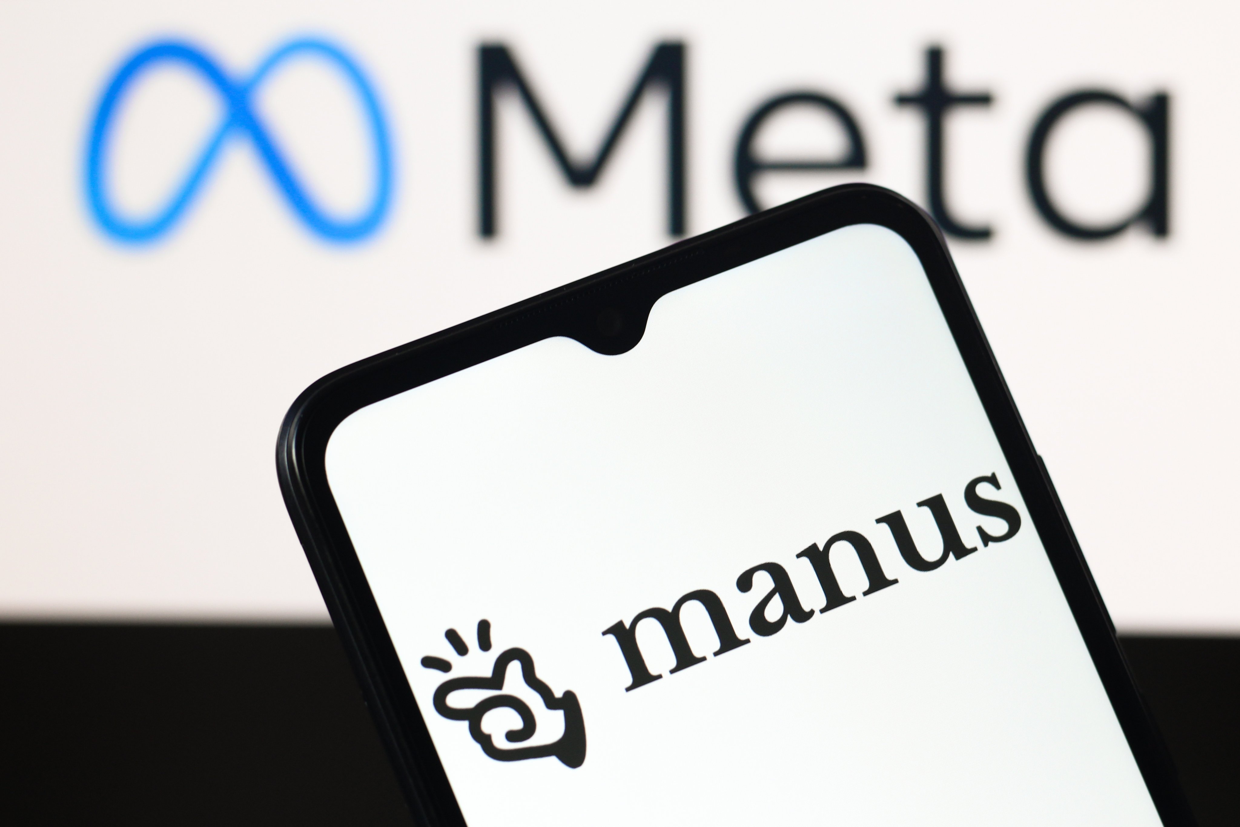 The Manus AI logo is seen displayed on a smartphone screen with the Meta logo in the background. Photo: Getty Images