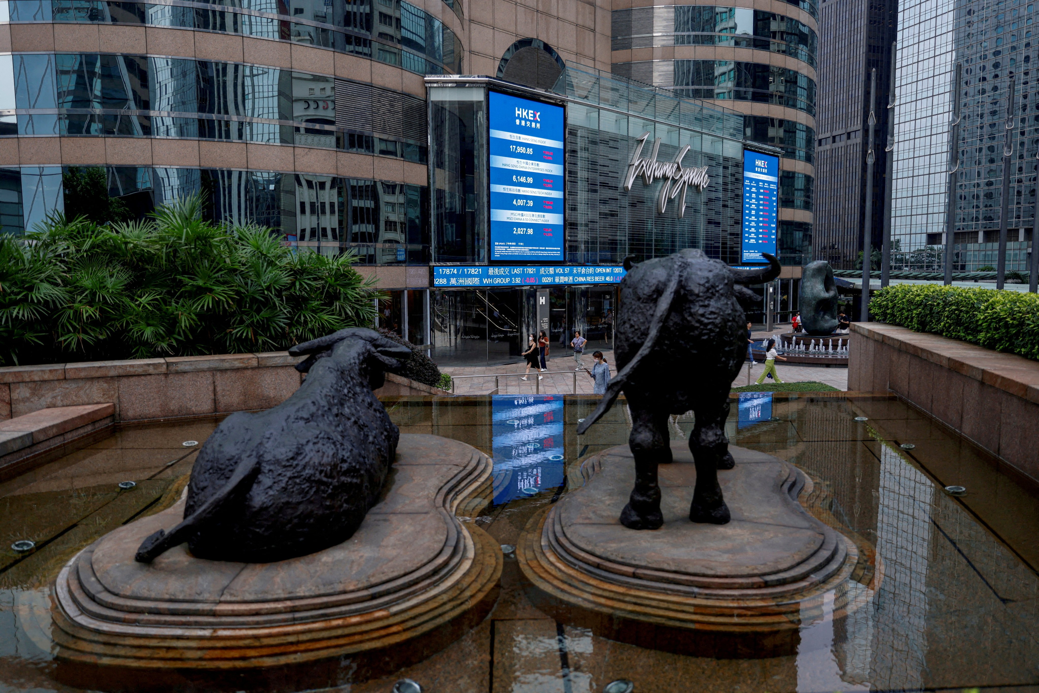 Bull statues sit in front of screens showing stock prices outside Exchange Square in Hong Kong on August 18, 2023. Photo: Reuters