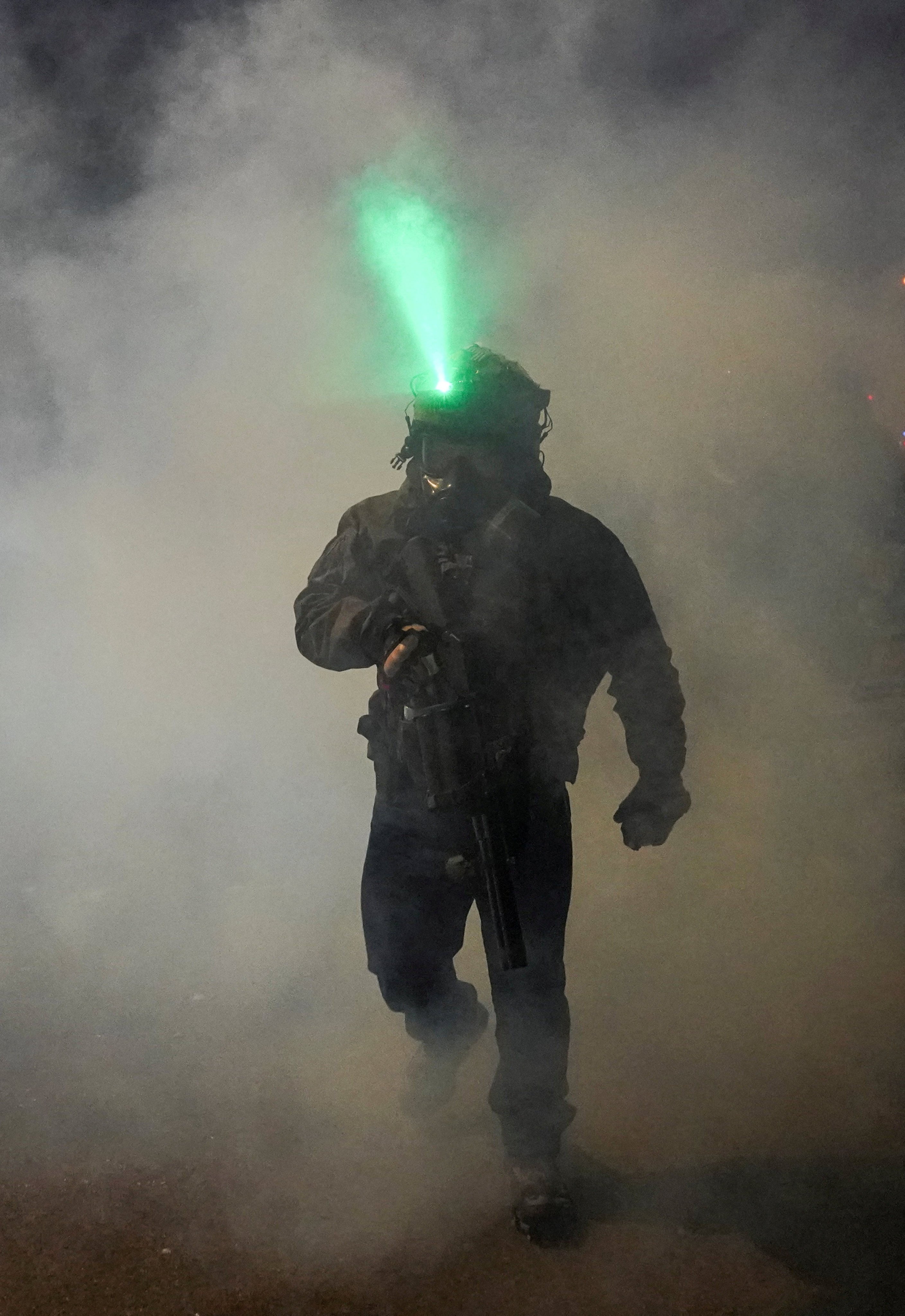 A federal agent walks through tear gas smoke after it was used on protesting community members in  Minneapolis on Wednesday. Photo: Reuters