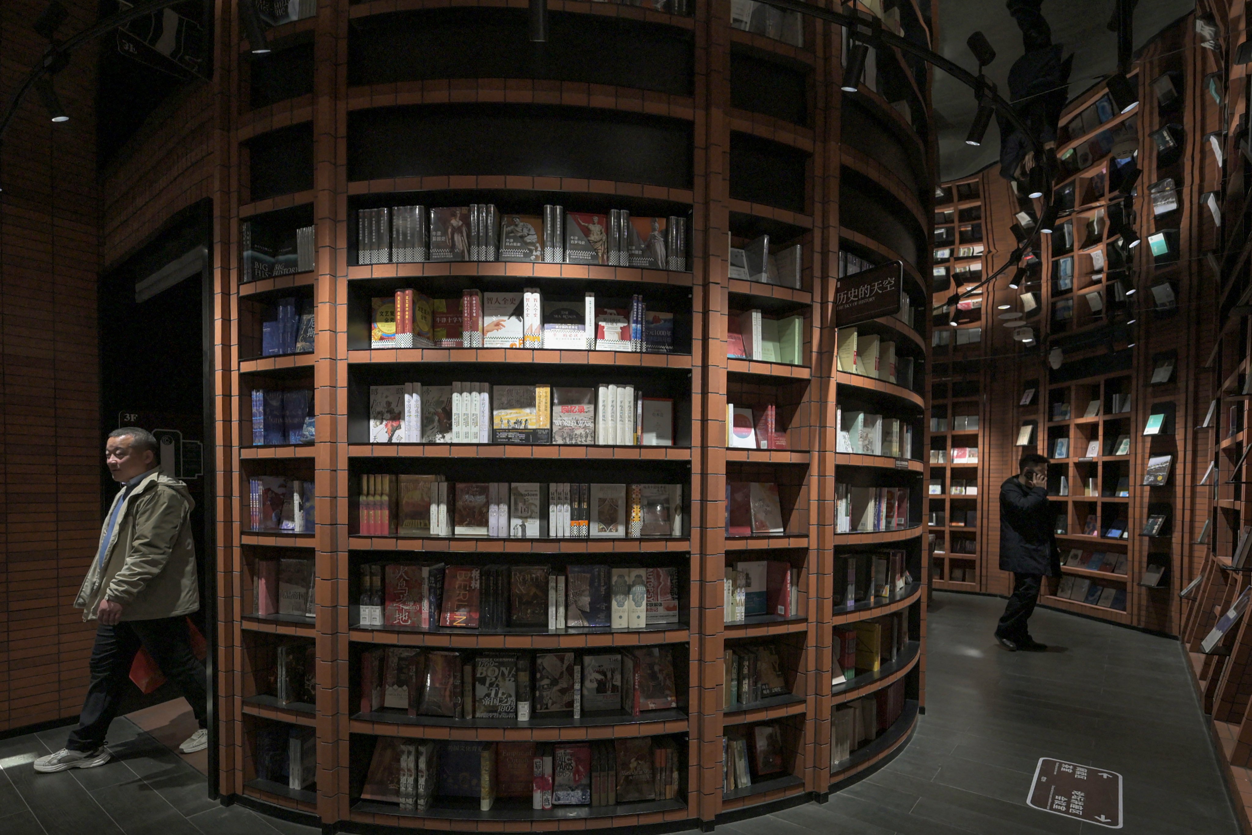 This picture taken on December 9, 2025 shows people visiting a bookstore in Tianjin. Towering accordion steps and a fantastical spiral staircase greet visitors to a massive bookstore in northern China’s Tianjin, where its striking interior is a bigger draw for selfie snappers than scholars. (Photo by Adek BERRY / AFP) / TO GO WITH CHINA-SOCIAL-BOOKS-ARCHITECTURE BY MARY YANG
