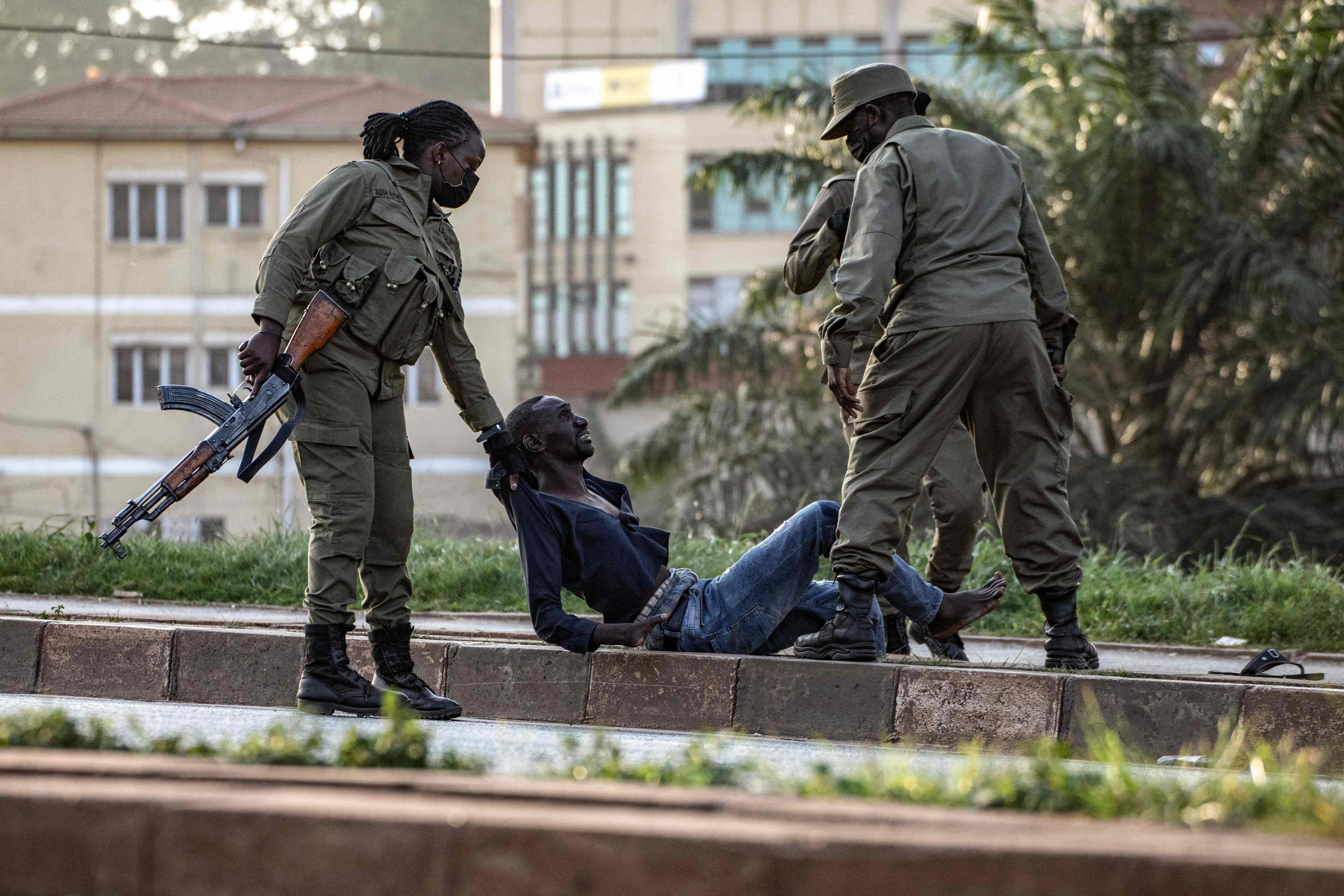 Police officers detain a voter on the ground near a polling station in Kampala on Thursday. Photo: AFP