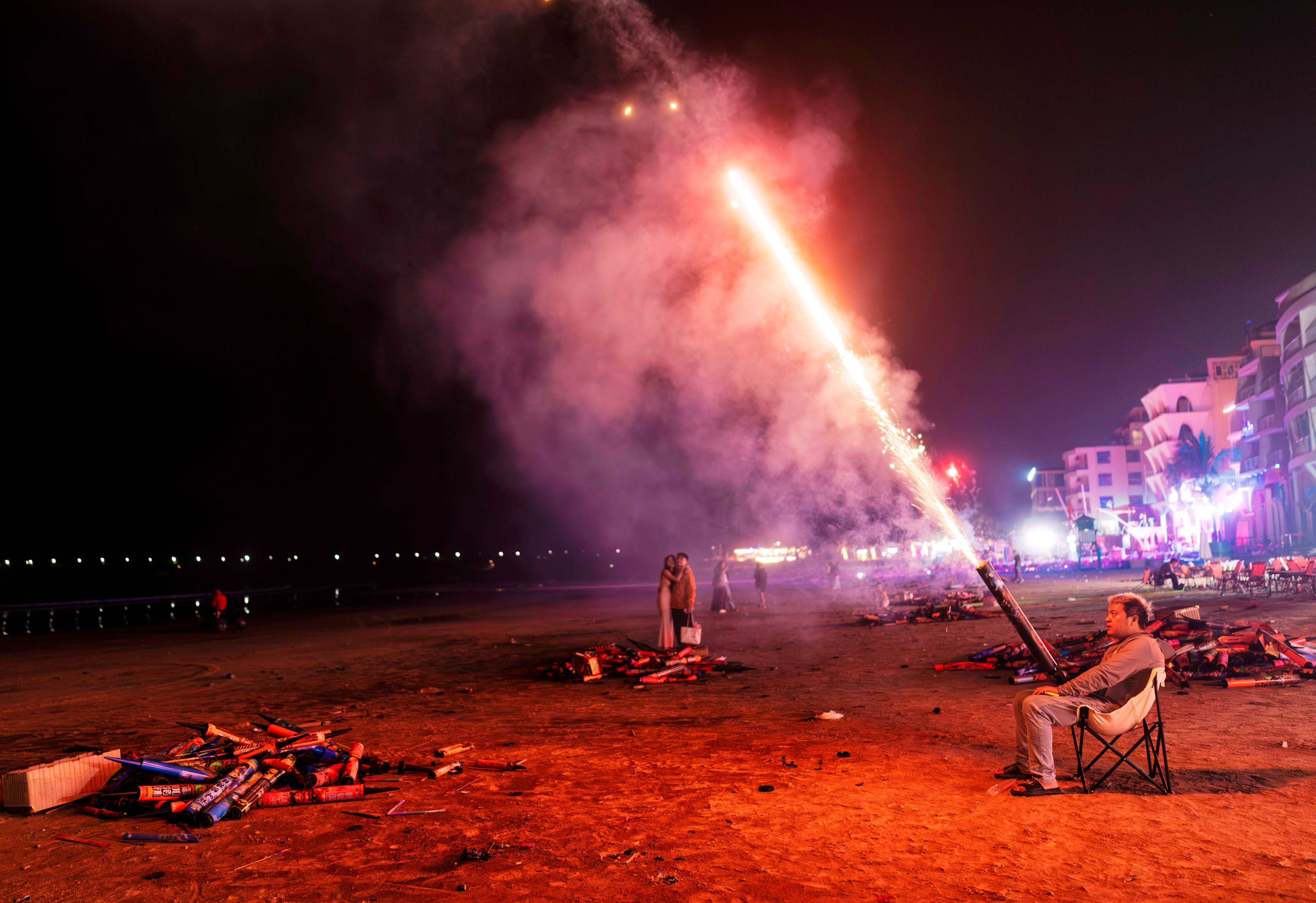 A man sets off fireworks to celebrate New Year on the beach in Houhai village, Hainan on January 1. Photo: EPA