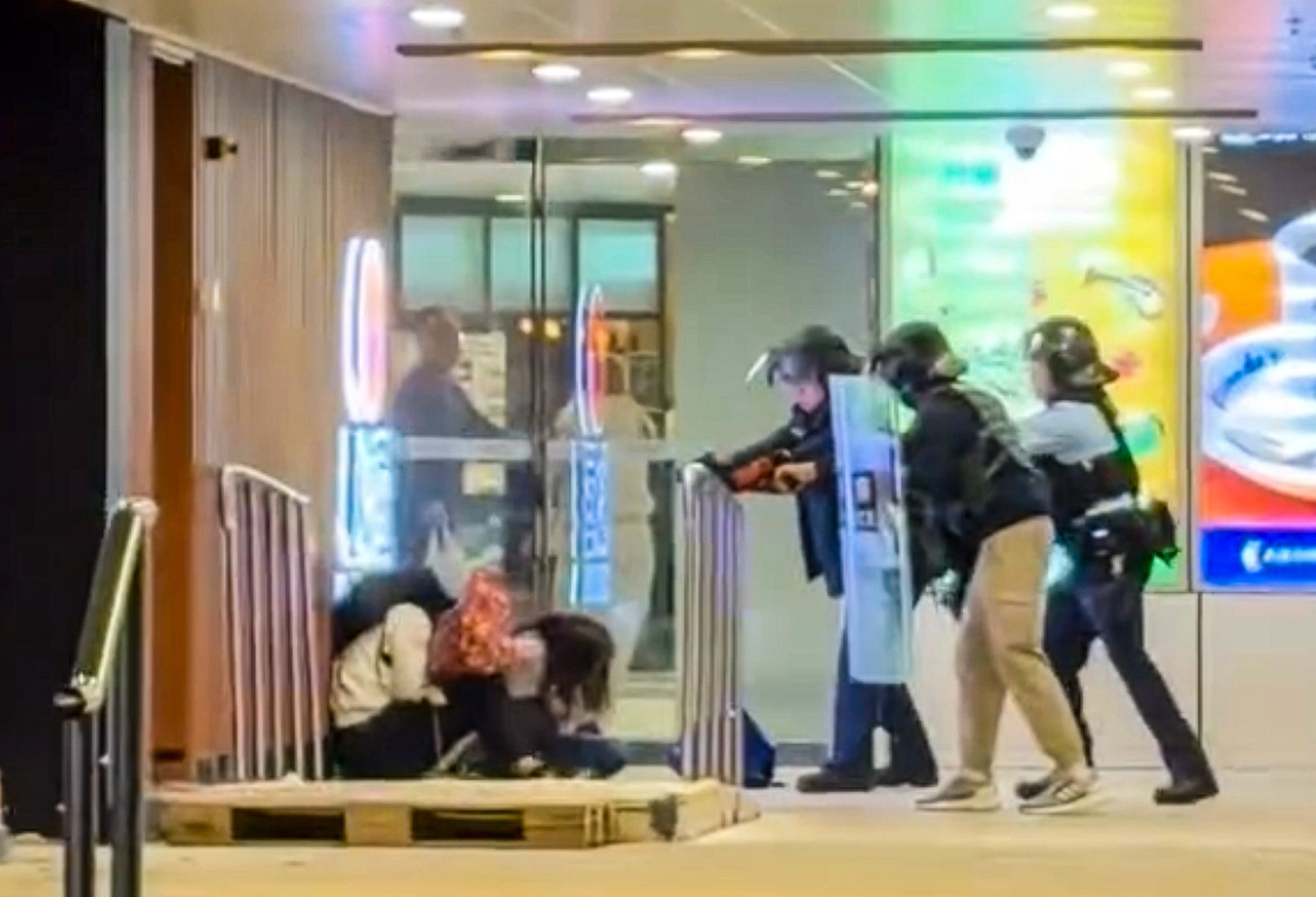 Officers draw their guns on a man who had taken a woman hostage while brandishing a 30cm knife at a shopping centre in Tuen Mun. Photo: Handout